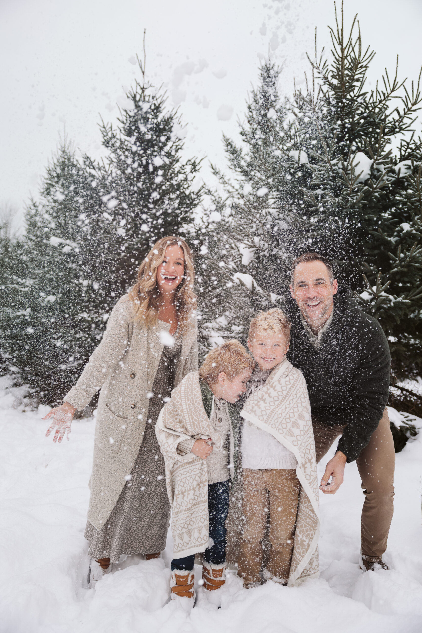 family of four throwing snow in the air during family portraits in northern michigan