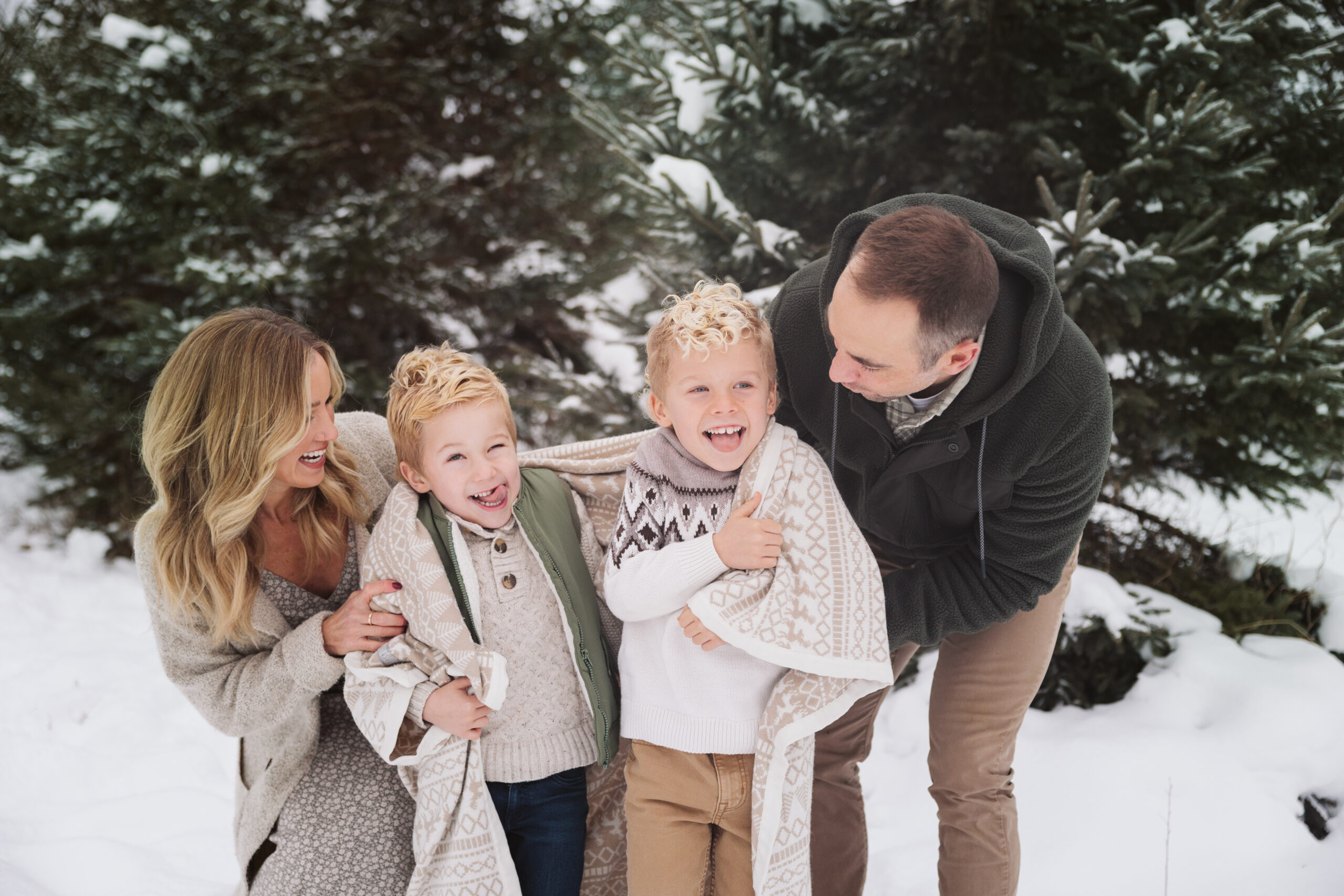 family of four laughing together during family portraits in northern michigan