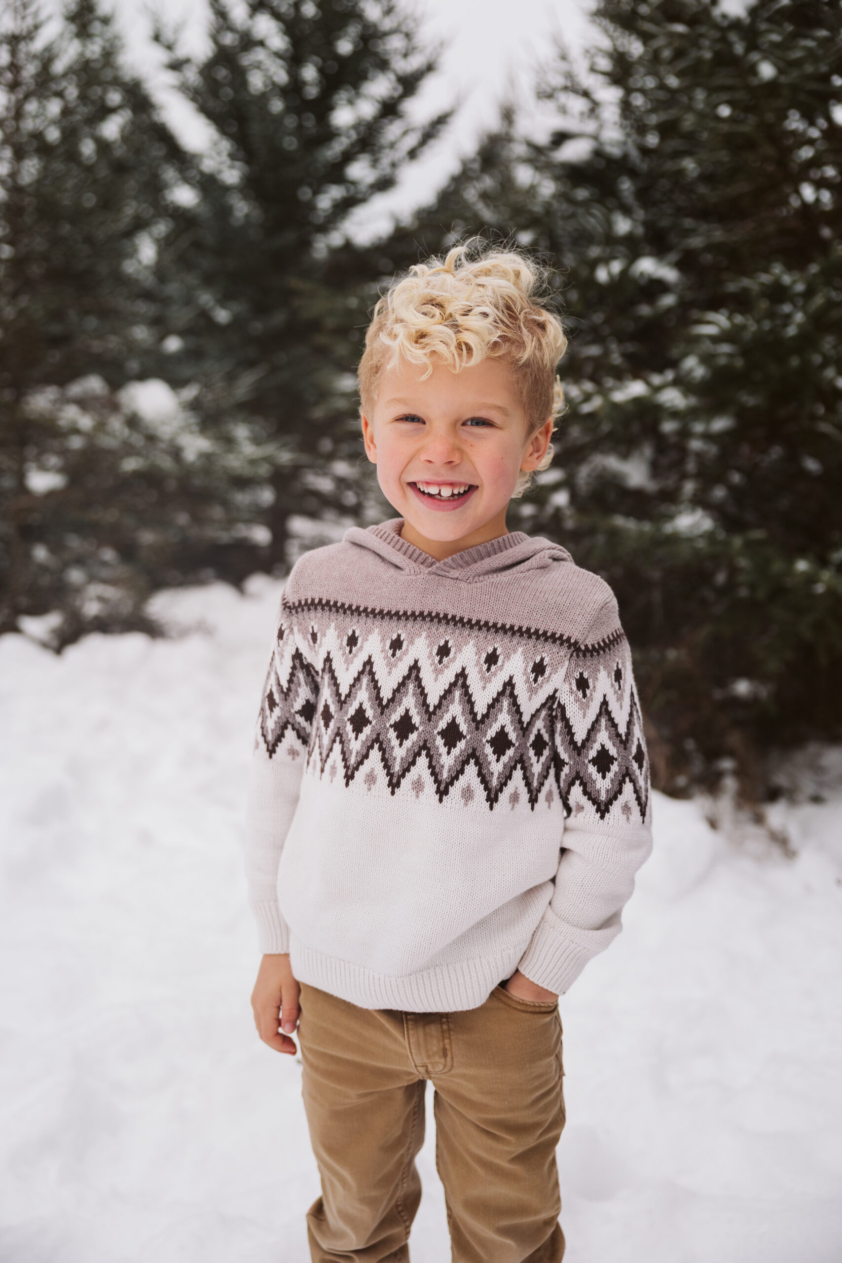 boy laughing in snow during family portraits in Traverse City Michigan