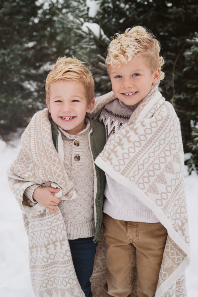 two brothers cuddled in blanket during christmas photos in traverse city