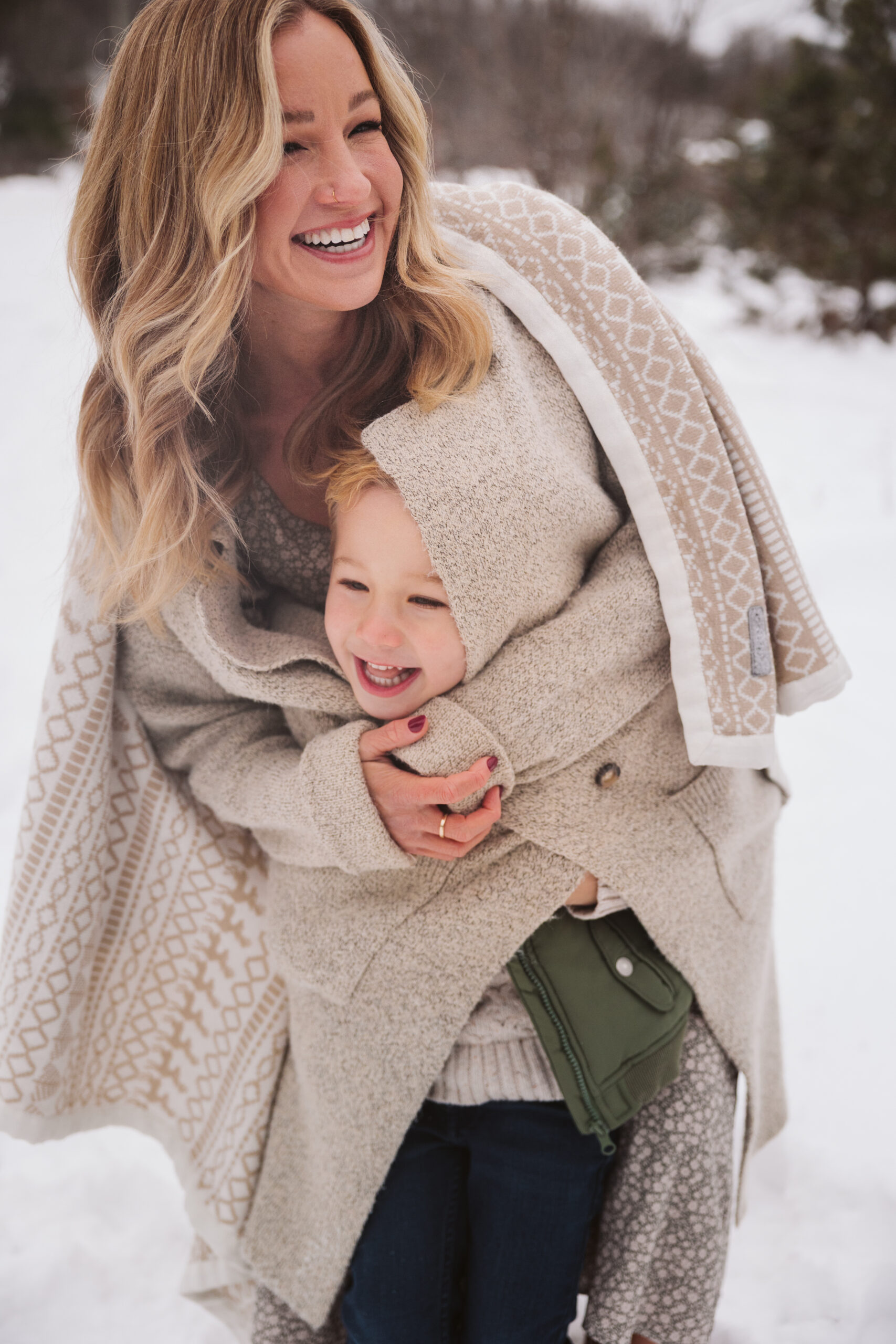 mom hugging her son wrapped in her coat during christmas photos in traverse city