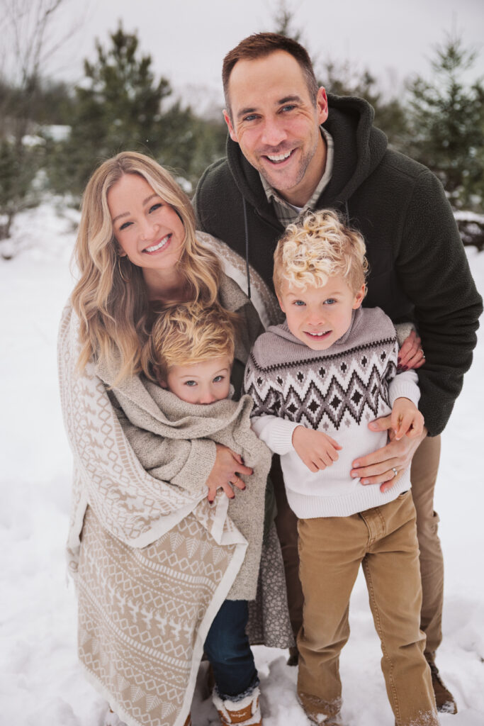 family cuddled up in blanket during christmas photos in traverse city