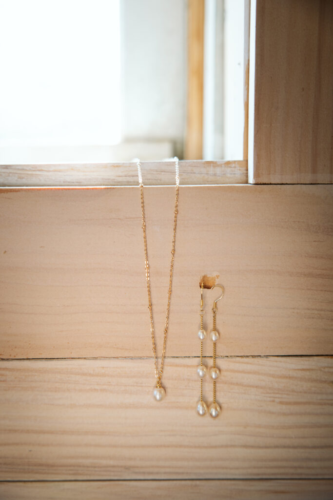 necklace and earings hanging from wall at wedding in glen arbor michigan photo by northern michigan photographer