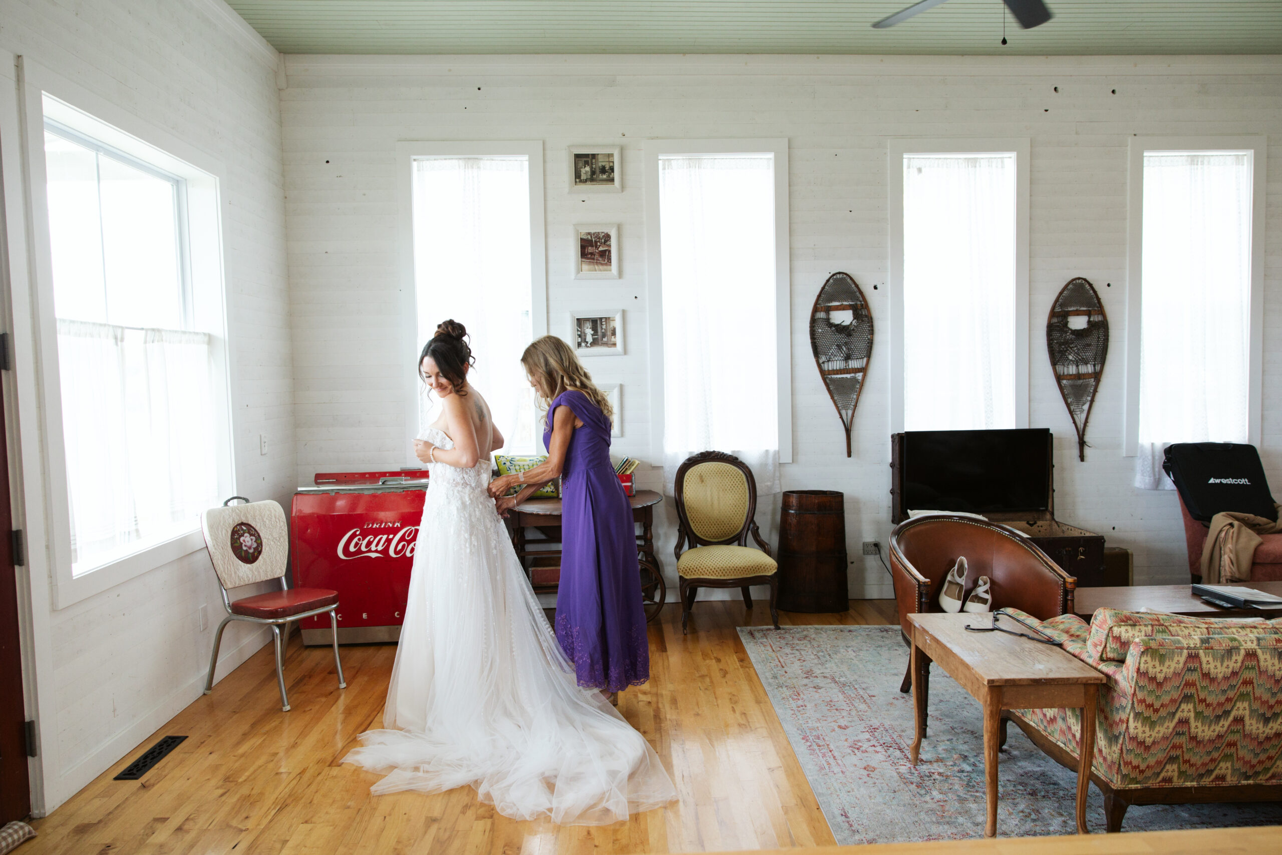 brides mother zipping up the brides dress at a general store at wedding in east jordan boathouse on lake charlevoix