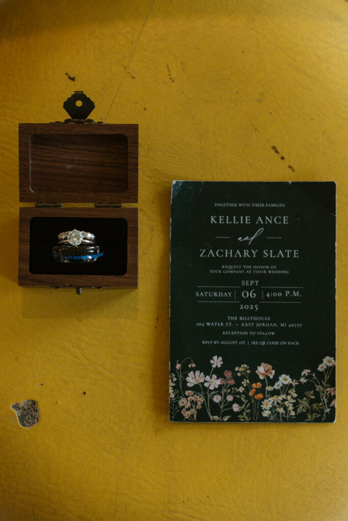 wedding ring and invitation sitting on general store stool airbnb at a general store at wedding in east jordan boathouse on lake charlevoix