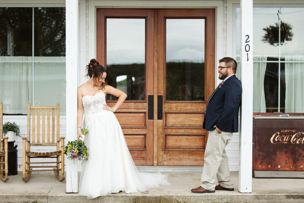 bride and groom leaning against posts at a general store at wedding in east jordan boathouse on lake charlevoix