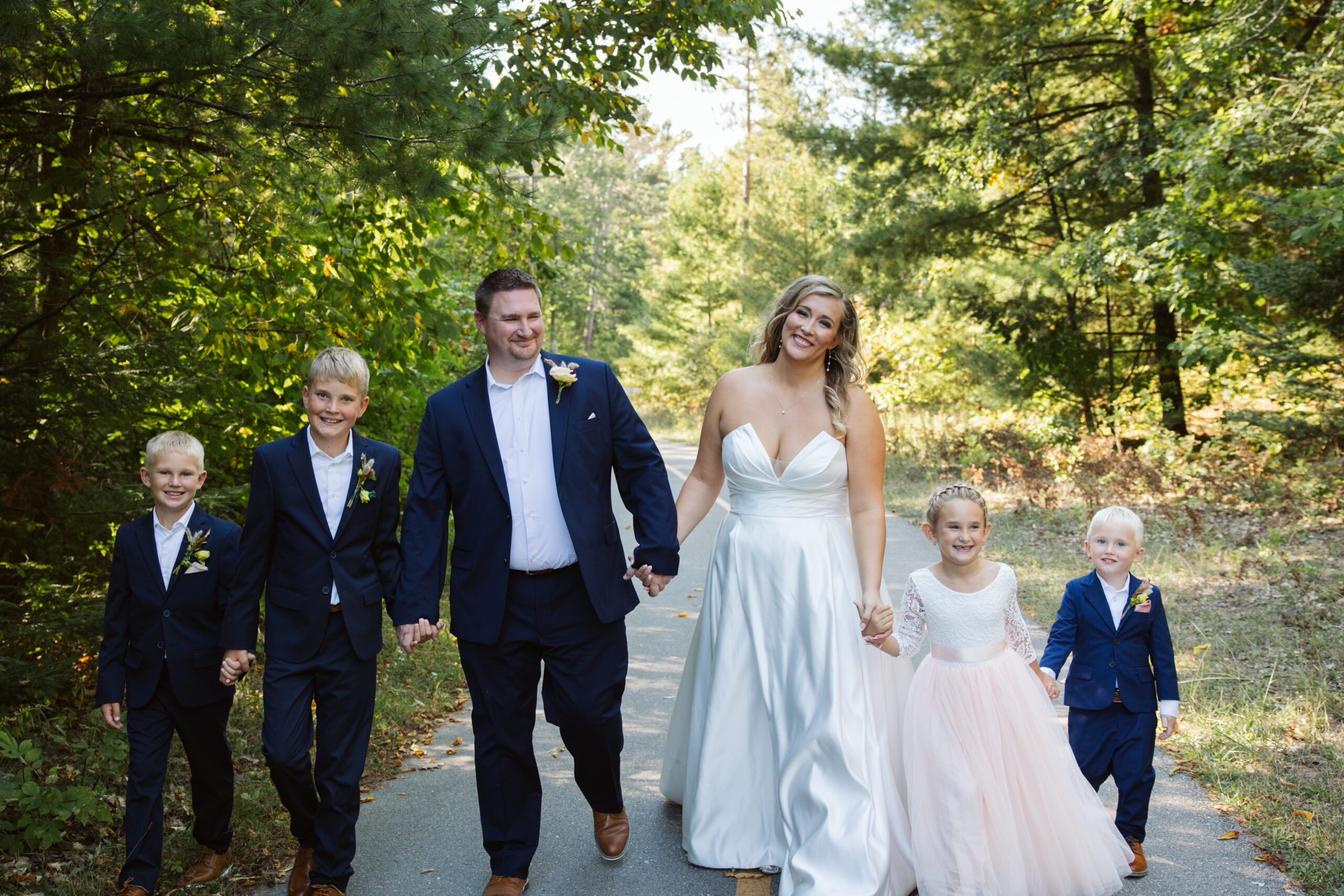 bride and groom with their children walking down a trail in d h day park in glen arbor michigan