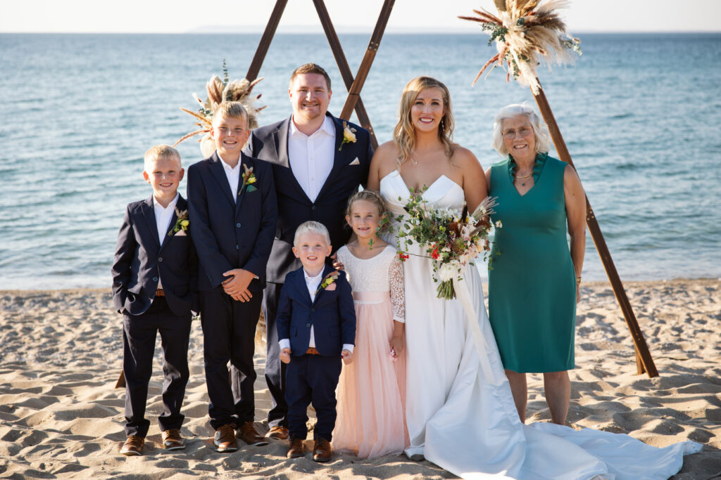 bride and groom with family under wedding arch on a lake michigan beach in glen arbor michigan