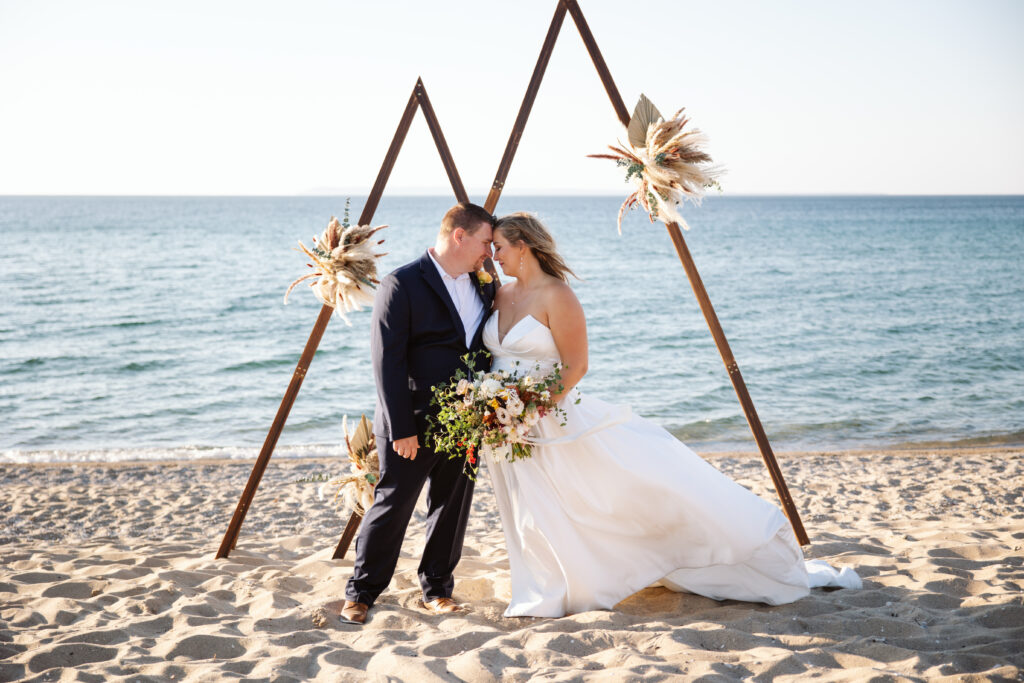 bride and groom under wedding arch on glen arbor beach in michigan