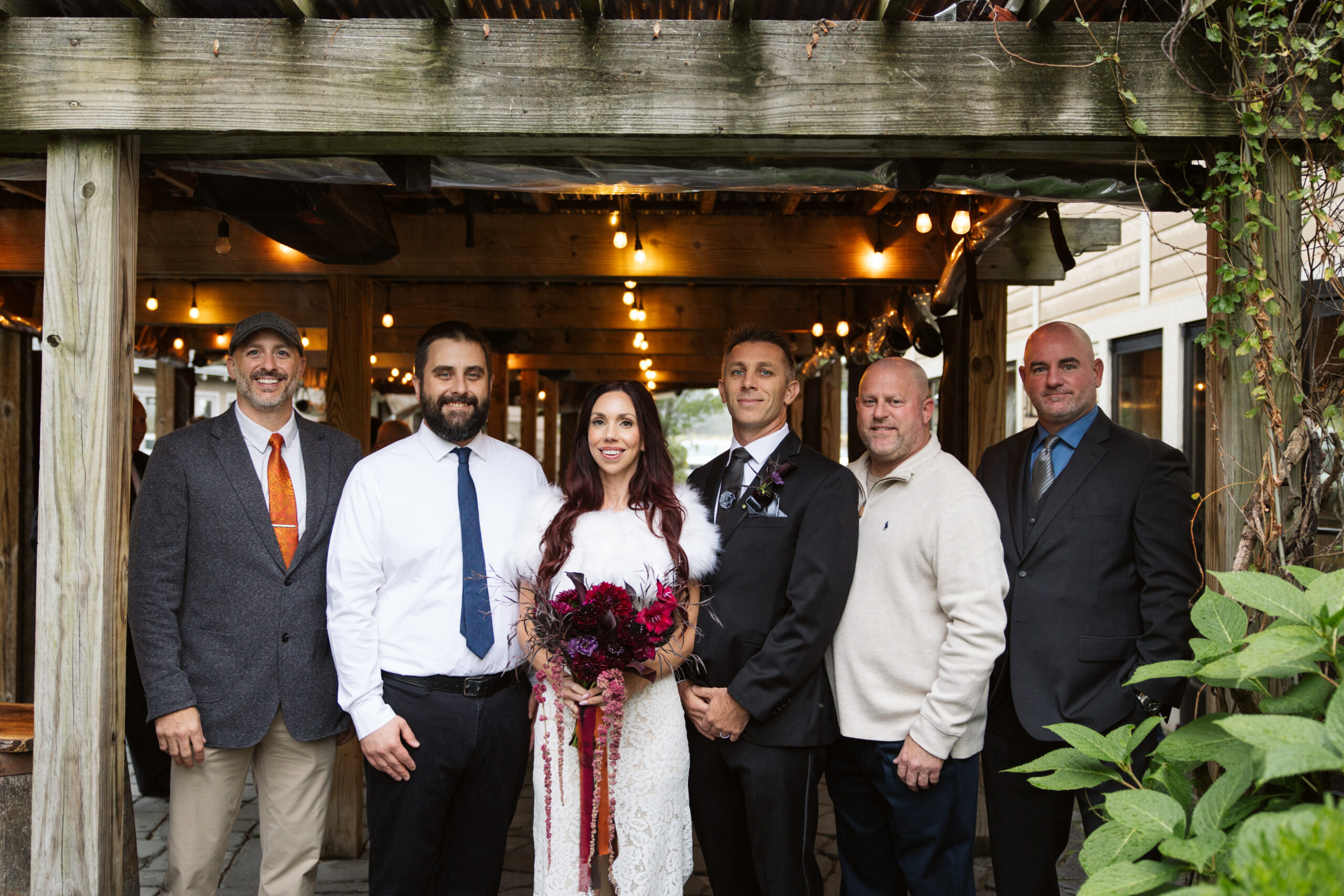 bride and groom with family during family portraits at peninsula cellars wedding in traverse city