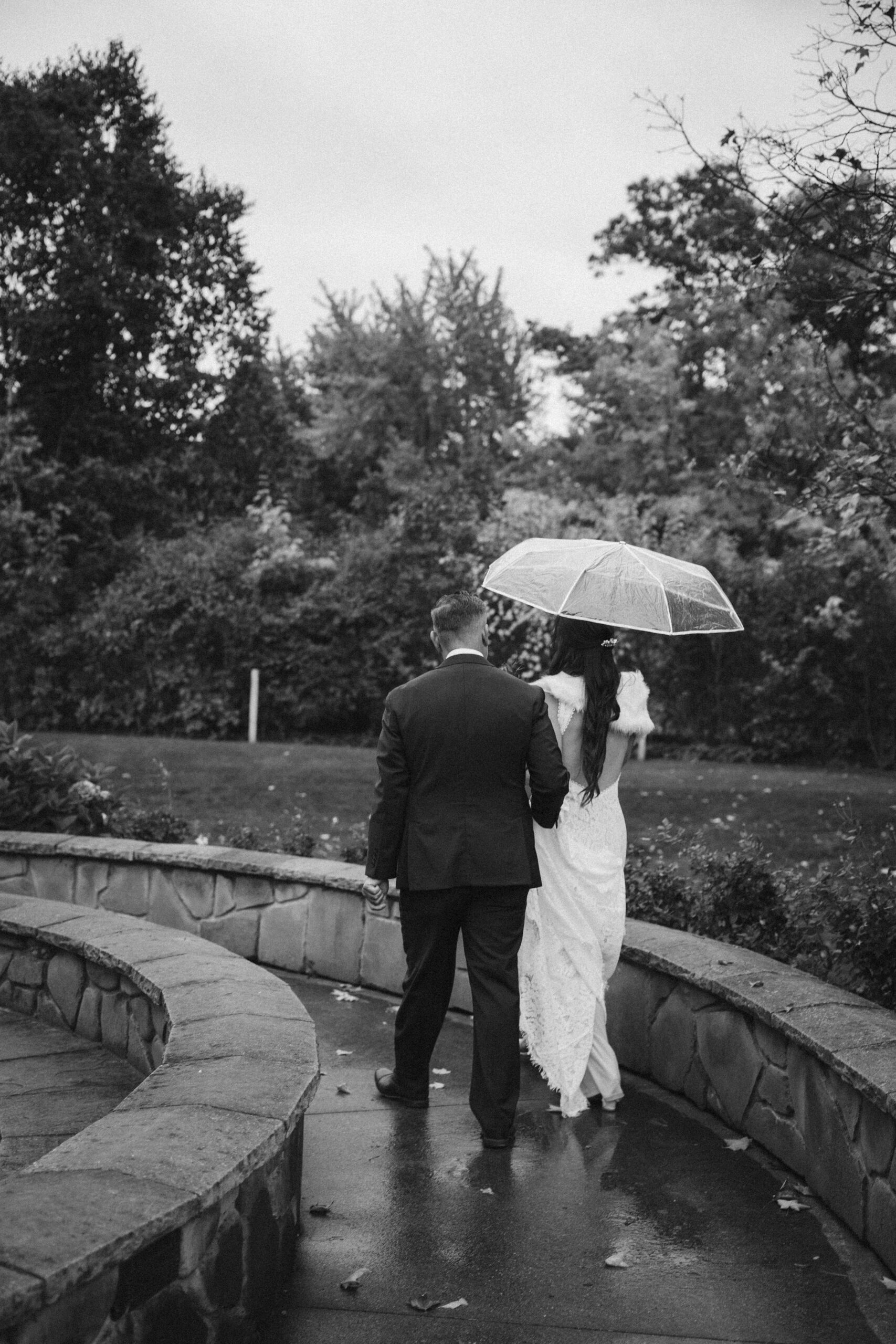 black and white of a bride and groom walking on a stone path at peninsula cellars