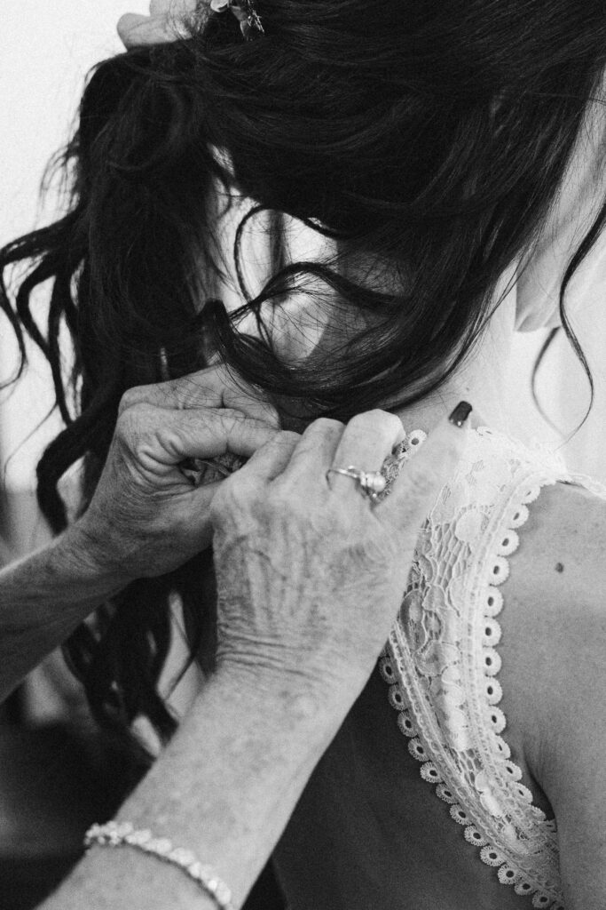 black and white close up of the mother of the bride lacing up her daughters dress at peninsula cellars in traverse city