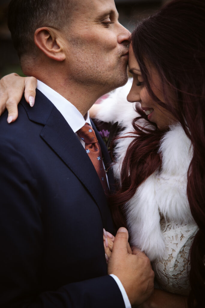 close up of a groom kissing his brides forehead at peninsula cellars wedding on old mission peninsula photo by traverse city wedding photographer