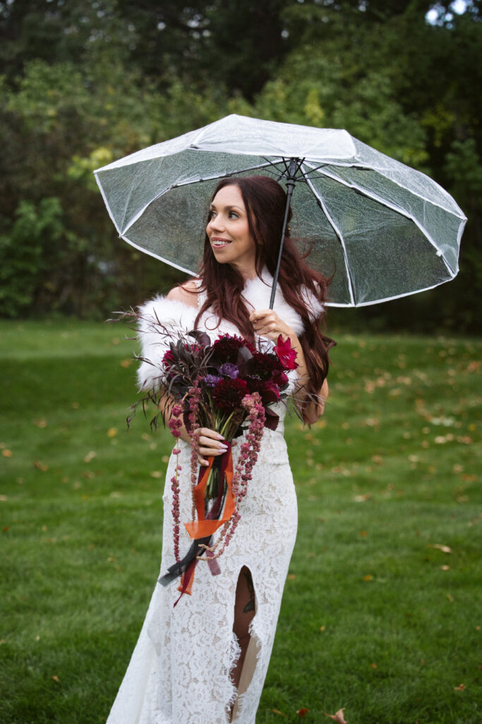 Peninsula-Room-Wedding--28 bride standing in the rain with an umbrella at peninsula cellars in traverse city