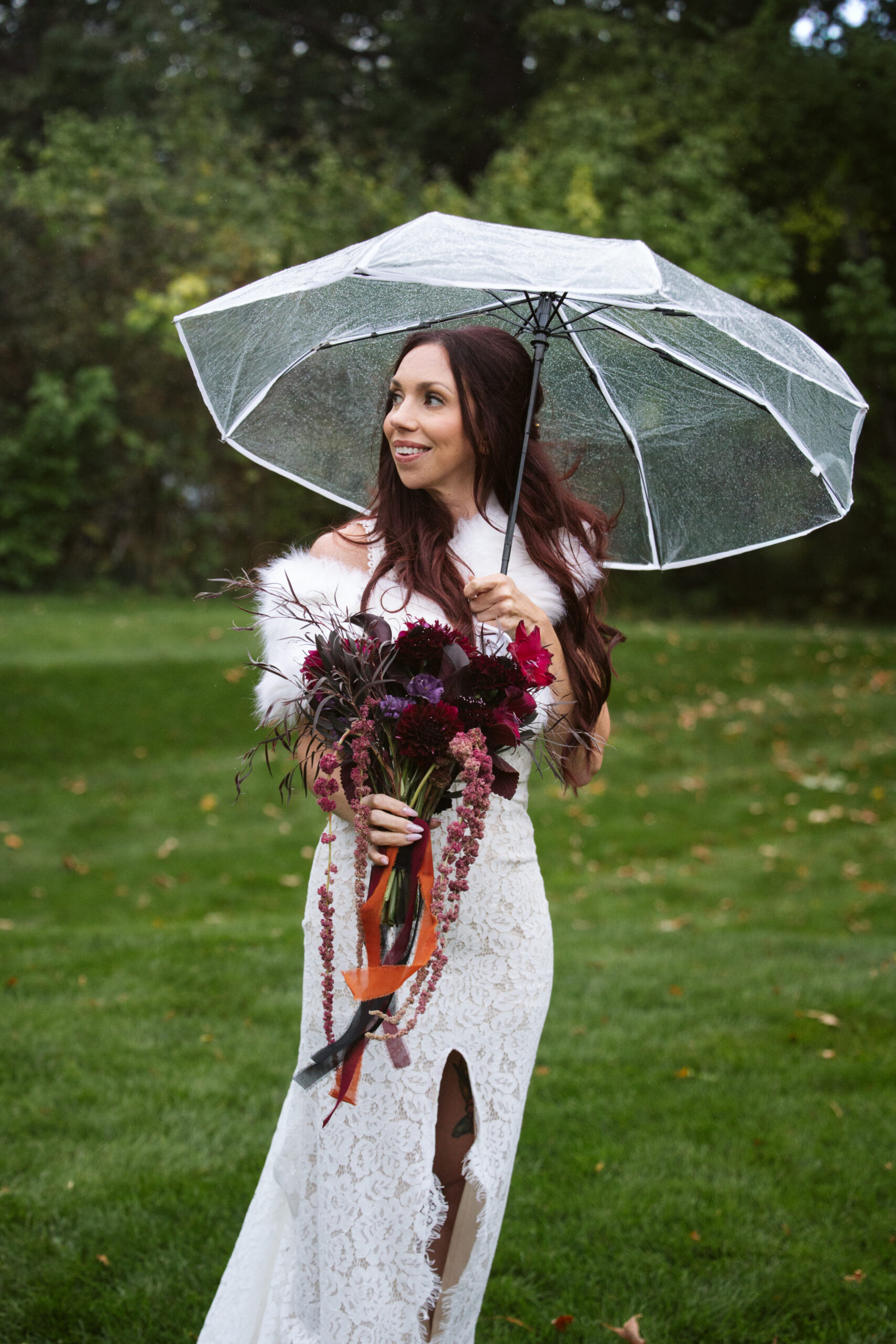 bride standing in the rain with an umbrella at peninsula cellars in traverse city
