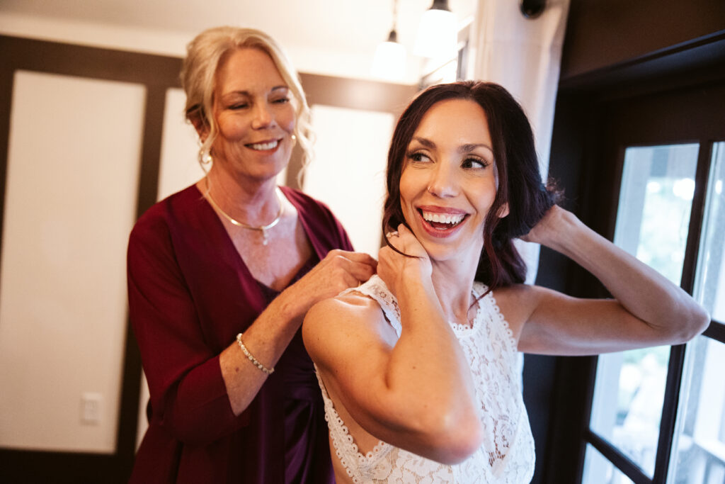 mother of bride lacing up her daughters wedding dress before ceremony at peninsula cellars in traverse city