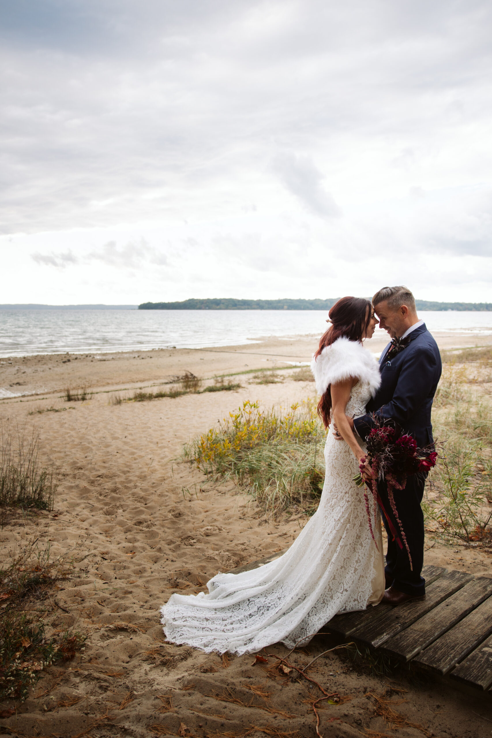 bride and groom holding each other on a beach on lake michigan during peninsula cellars wedding in traverse city michigan