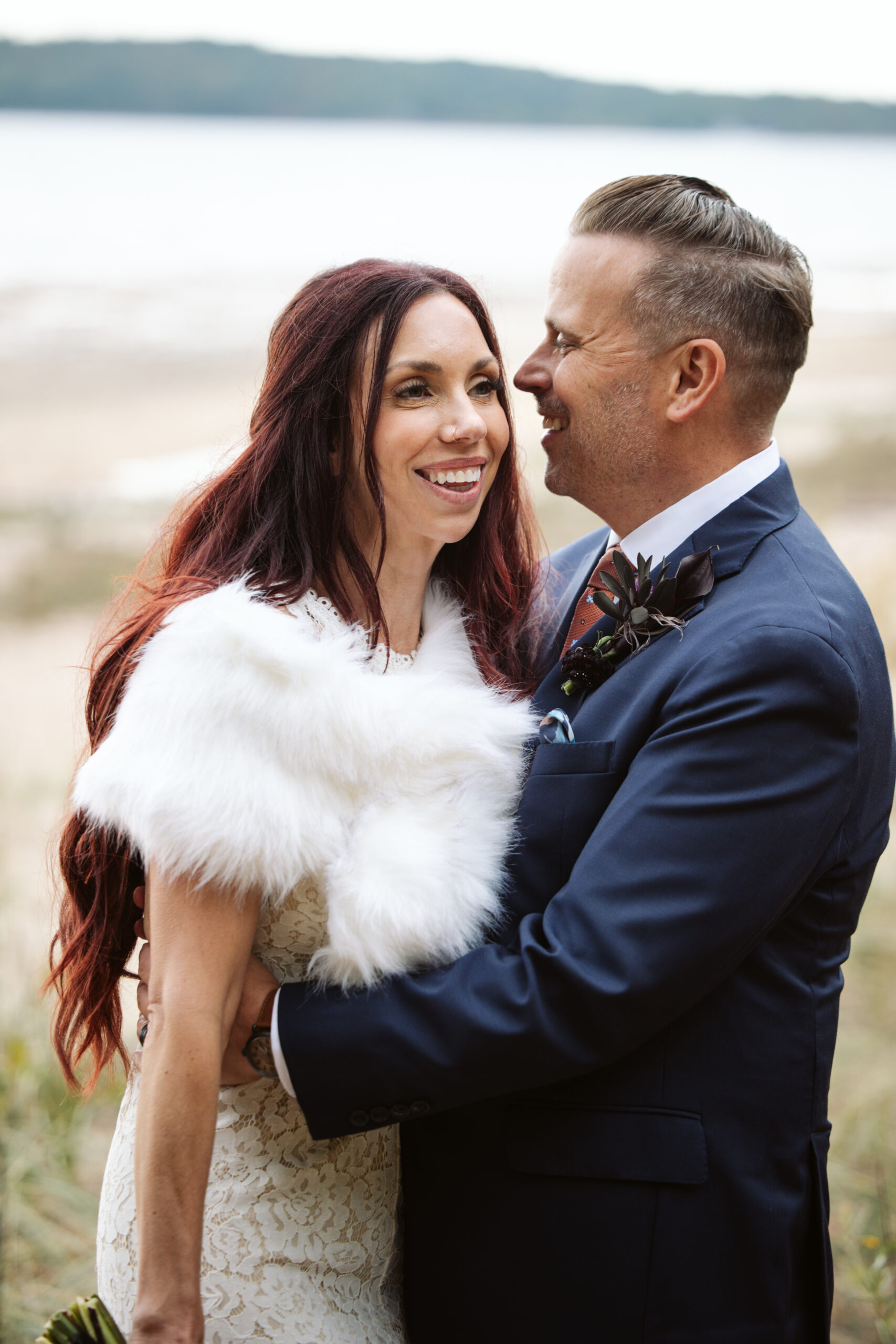 close up of bride and groom holding each other on lake michigan beach in traverse city