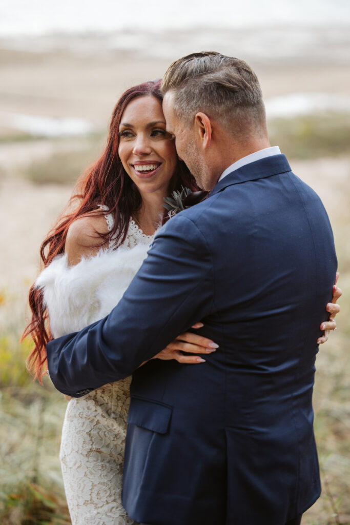 close up of bride and groom holding each other on lake michigan beach in traverse city