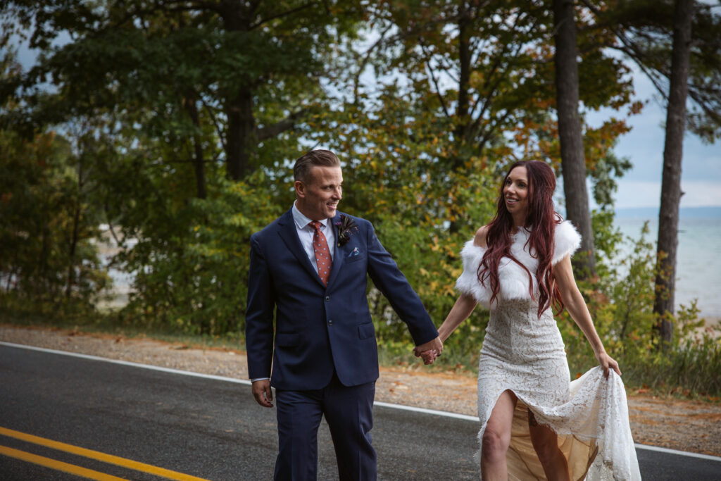 bride and groom walking across the road at peninsula cellars mission table wedding photo by traverse city wedding photographer
