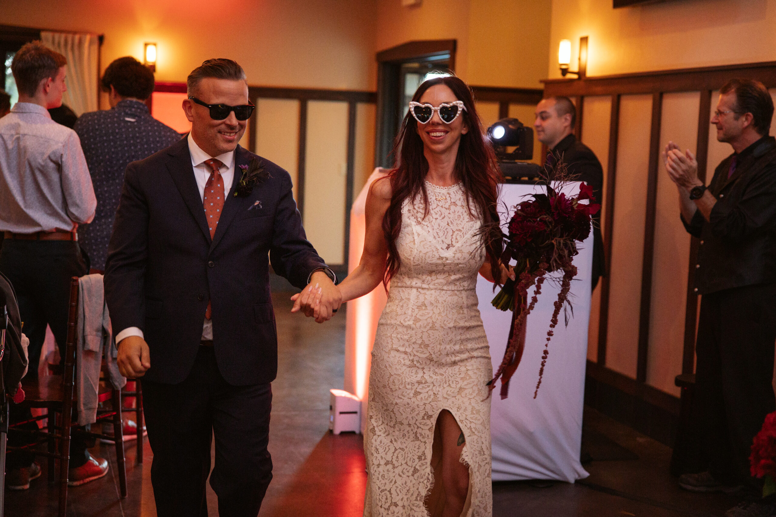 bride and groom walking in peninsula cellars reception hall with sunglasses smiling in traverse city wedding