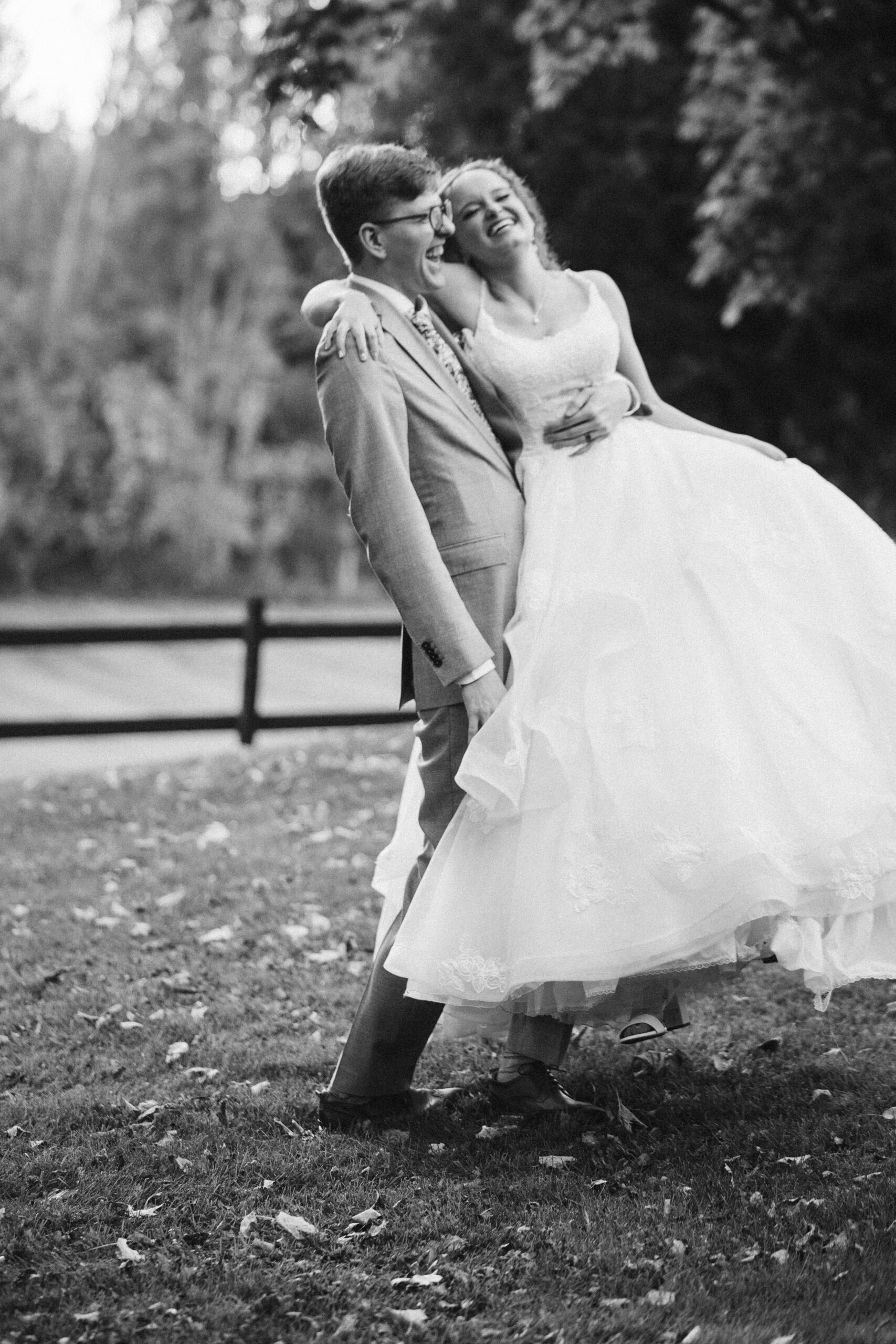 black and white of groom spinning his bride around playfully at starry night barn wedding in suttons bay michigan