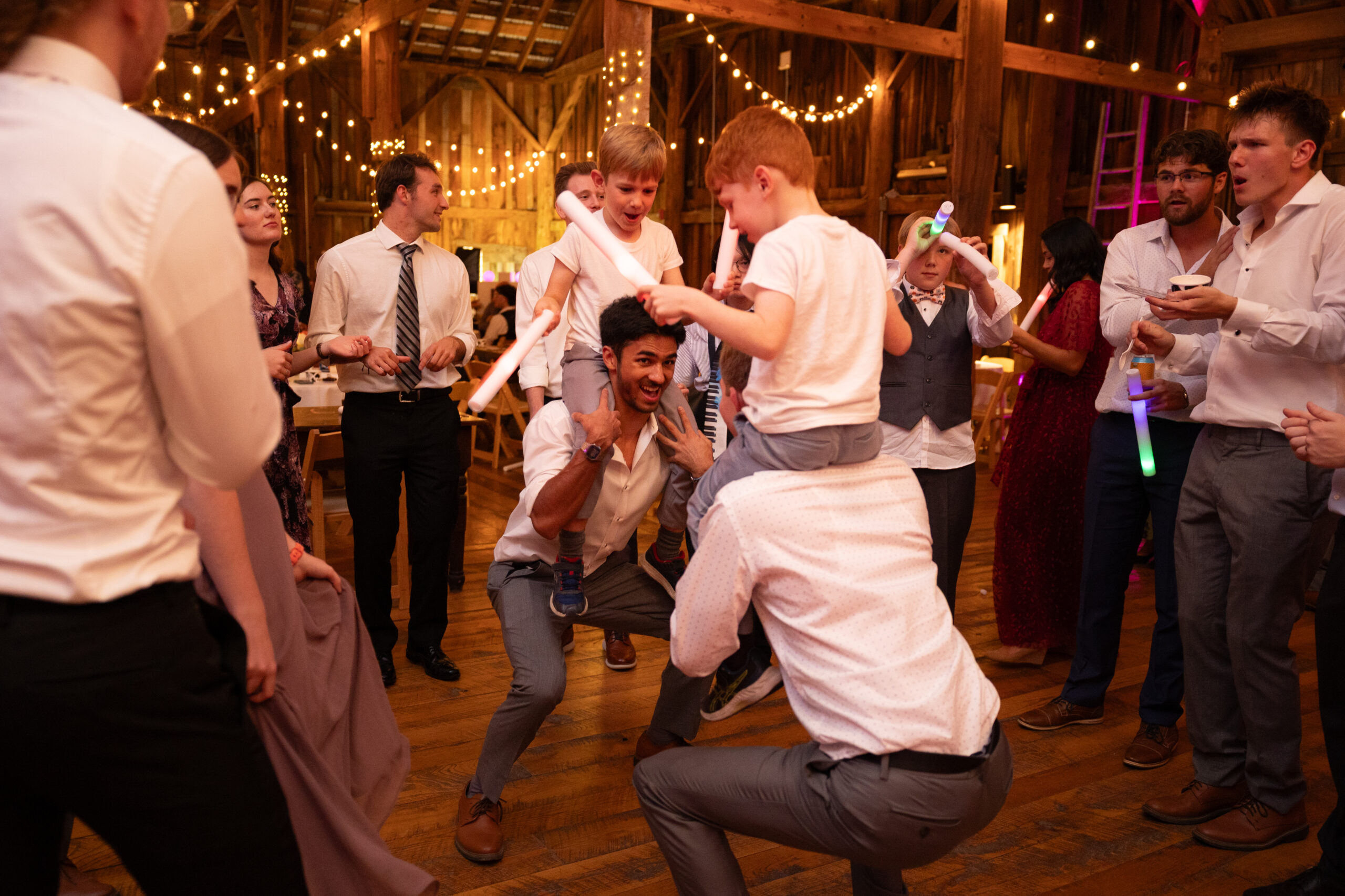men carrying kids on their shoulders during starry night barn reception in suttons bay michigan