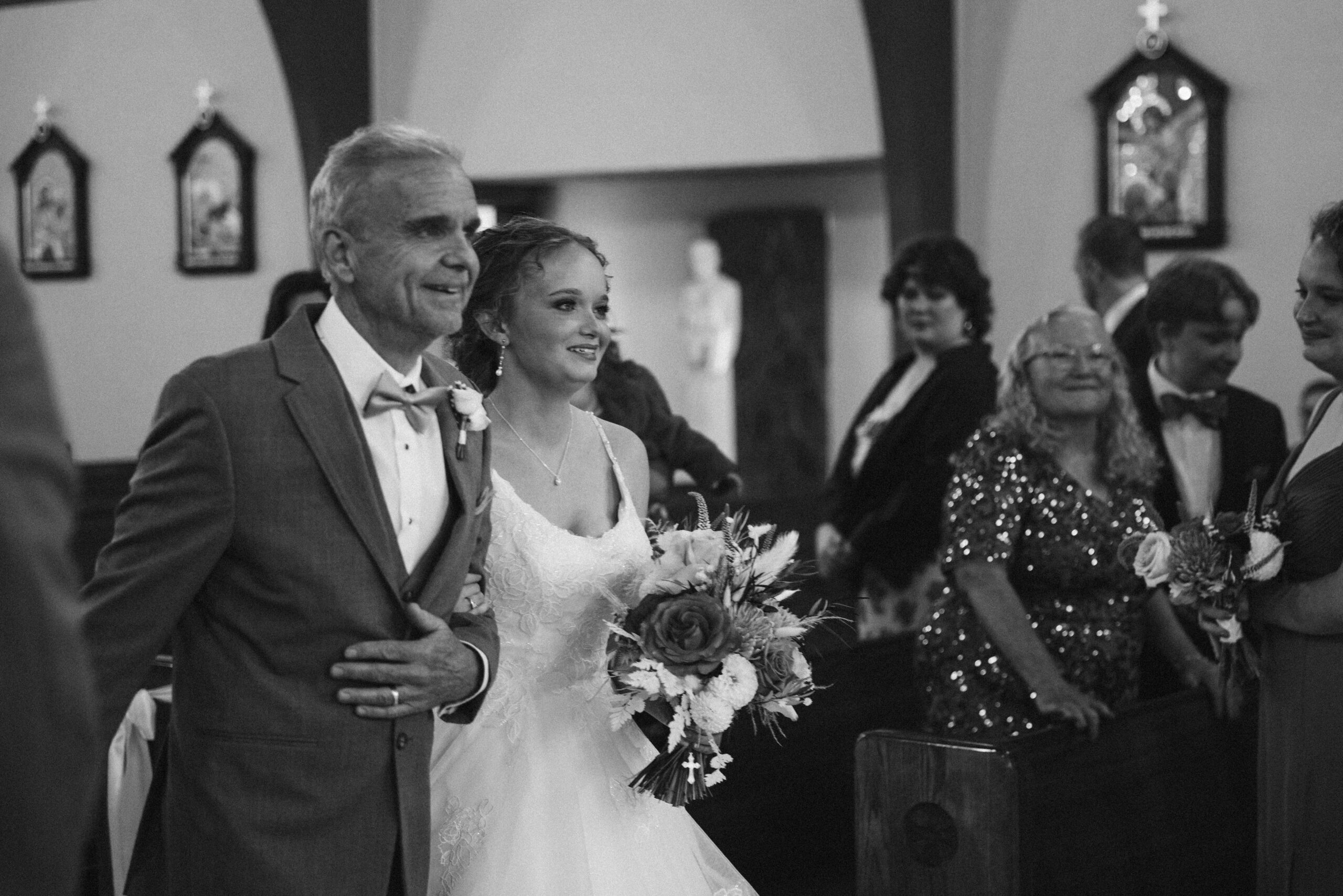 father of the bride walking bride down the aisle at immaculate conception in traverse city michigan wedding