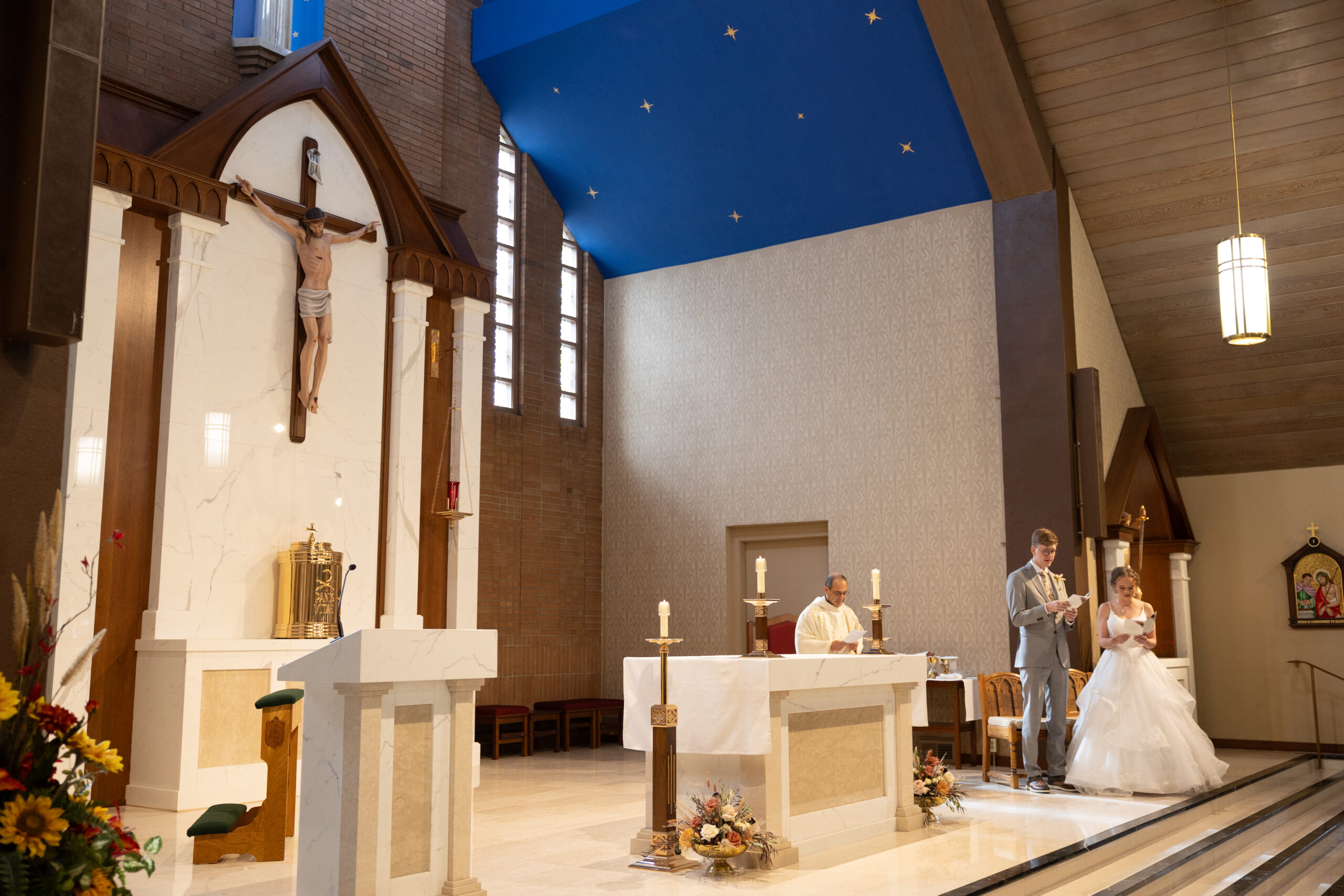 bride and groom sitting at alter at immaculate conception in traverse city michigan