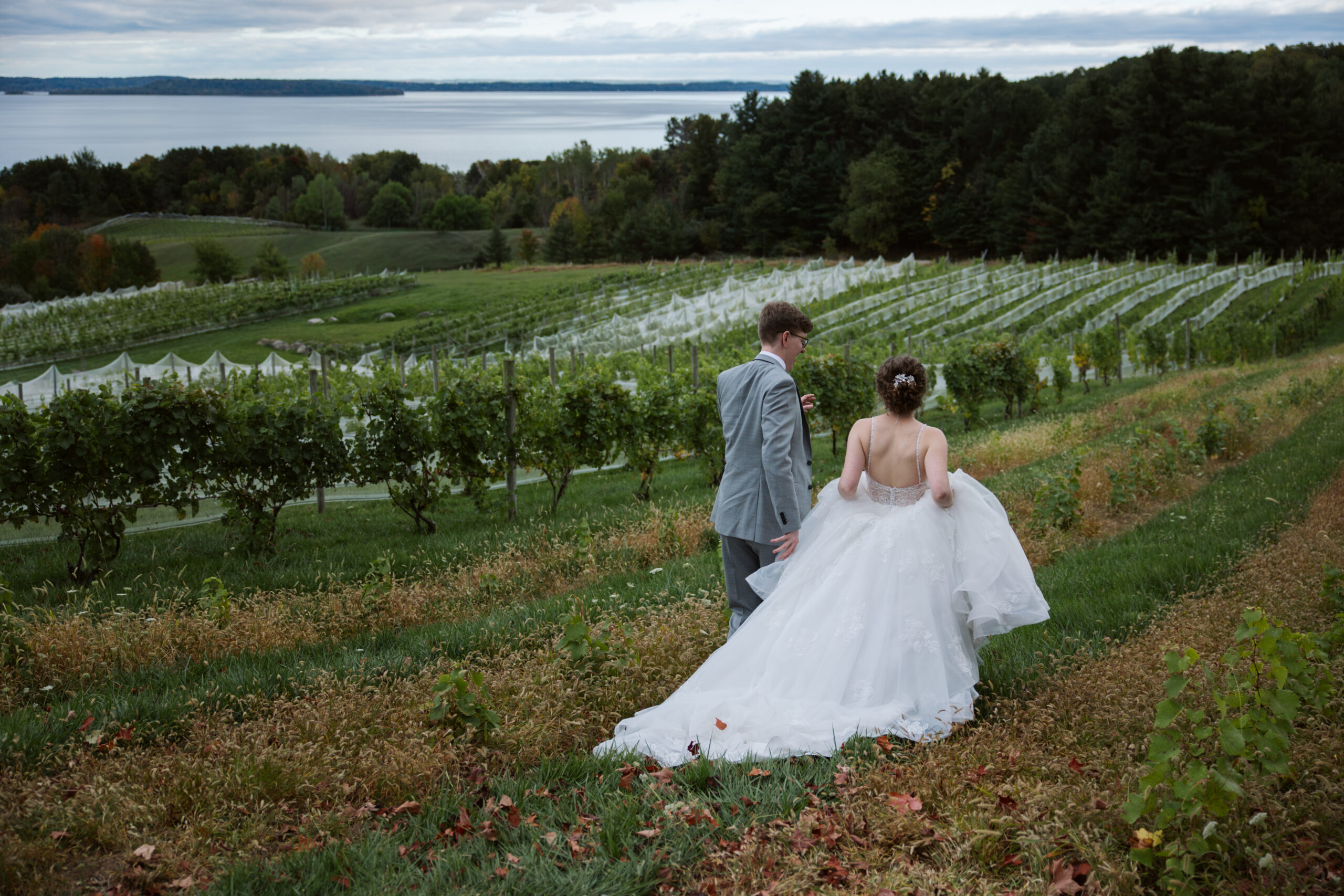 bride and groom running through vineyard in suttons bay michigan