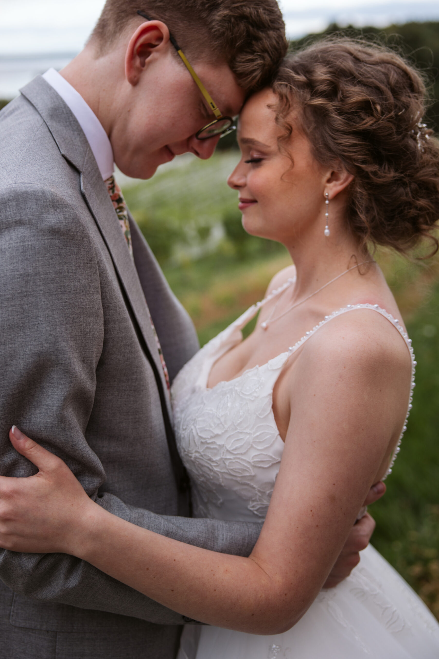 bride and groom with their foreheads together at vineyard on suttons bay michigan