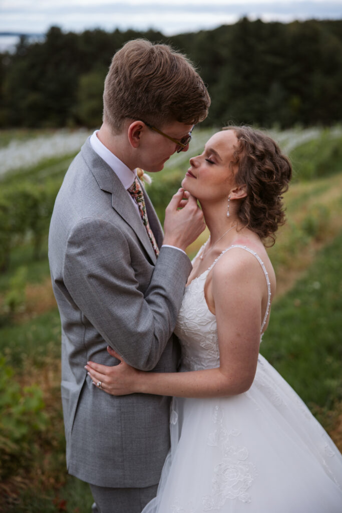 groom pulling his bride in for a kiss at vineyard in suttons bay michigan