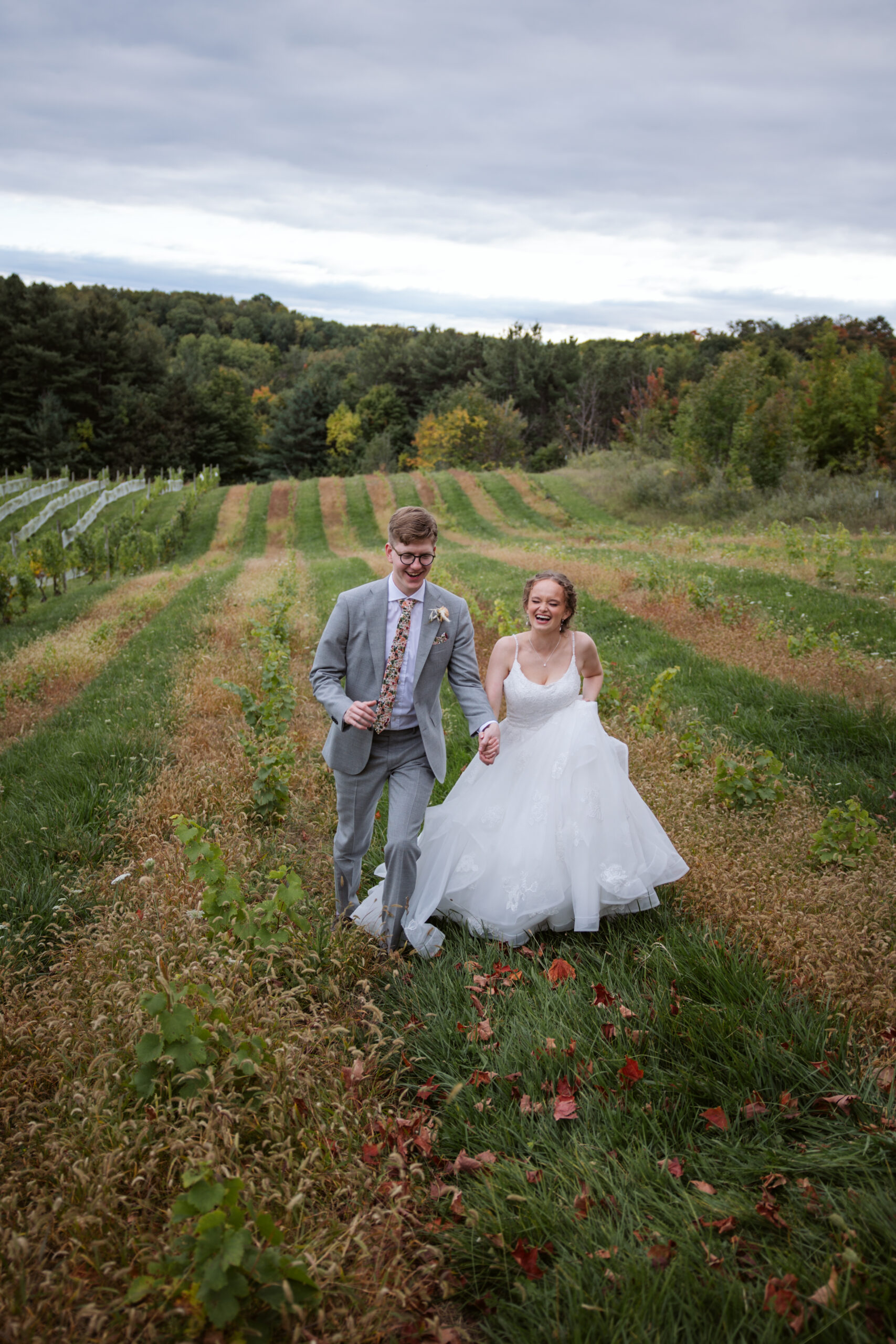 bride and groom walking through vineyard in suttons bay michigan