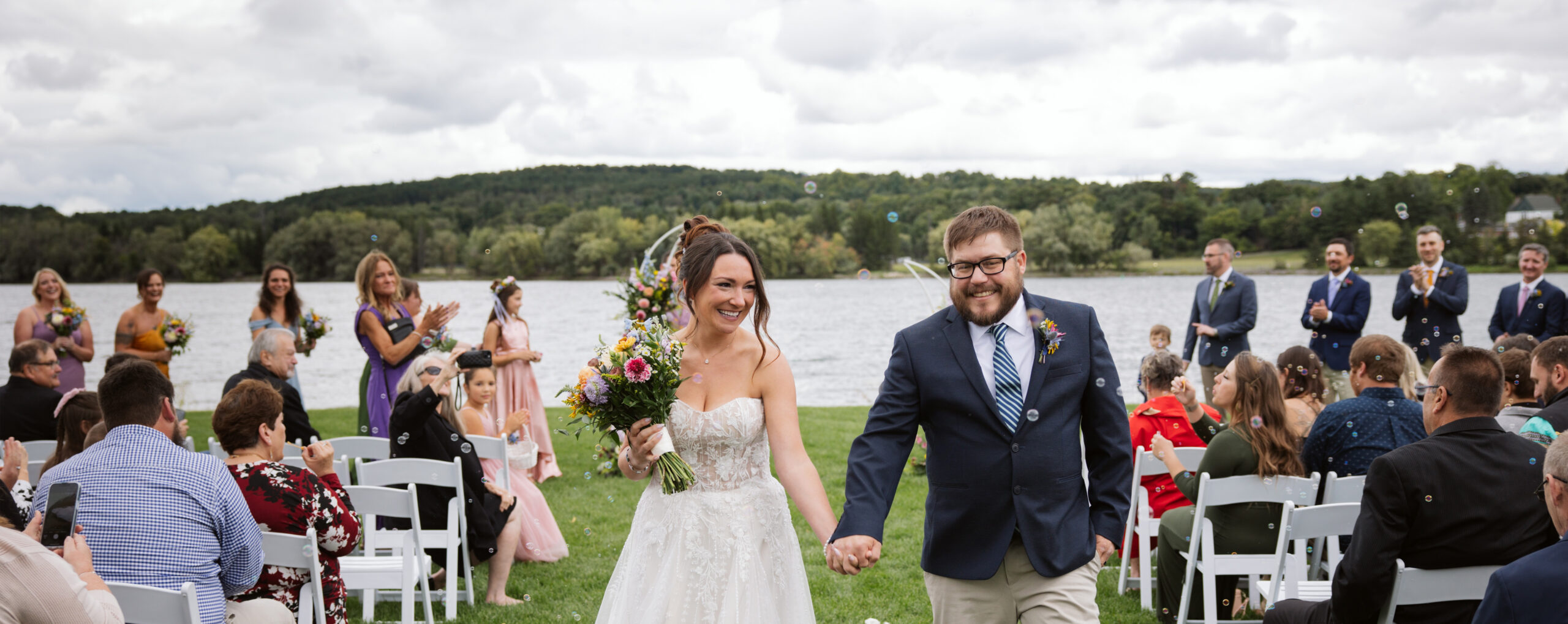bride and groom walking down aisle of their ceremony after getting married at the boathouse on lake charlevoix in east jordan