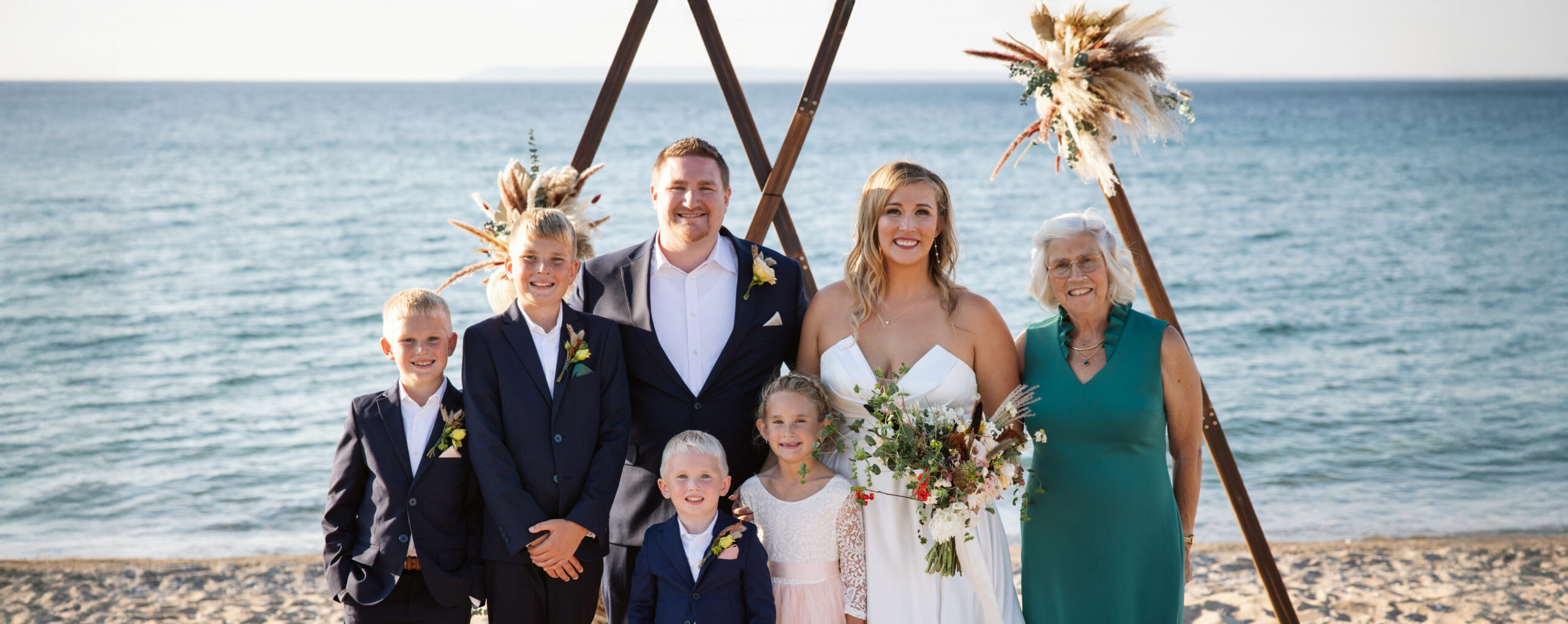 bride and groom with family under arch during lake michigan wedding in glen arbor