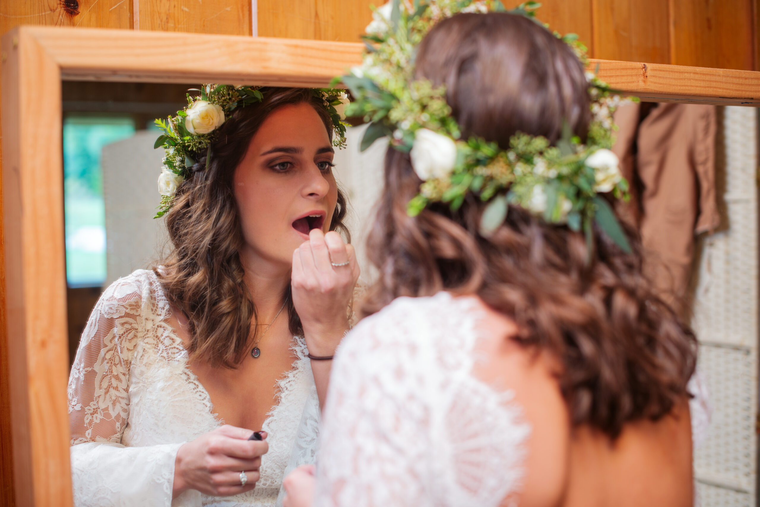 bride putting on lipstick during wedding at twin lakes campground in traverse city