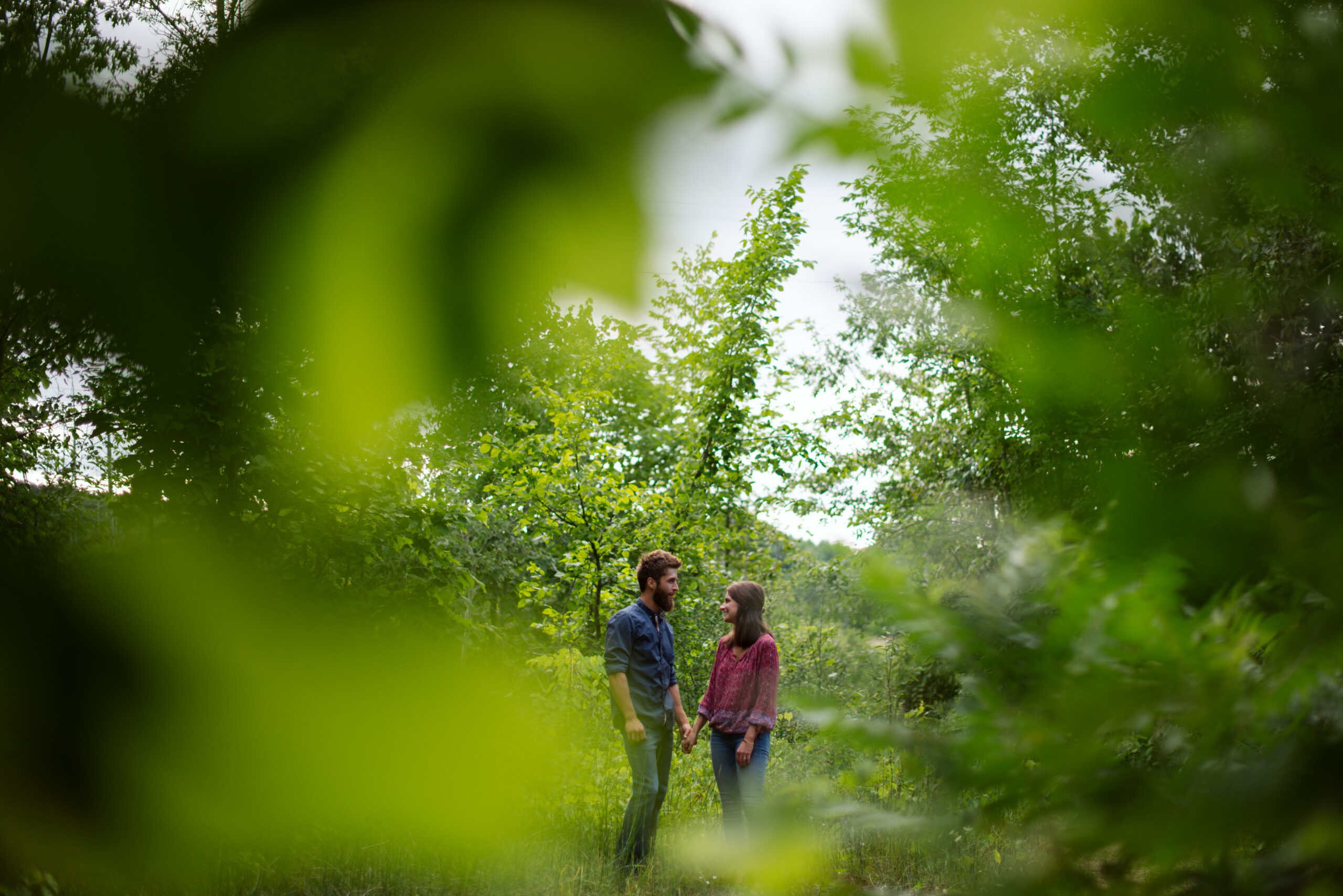man and woman standing in the woods during traverse city engagement session