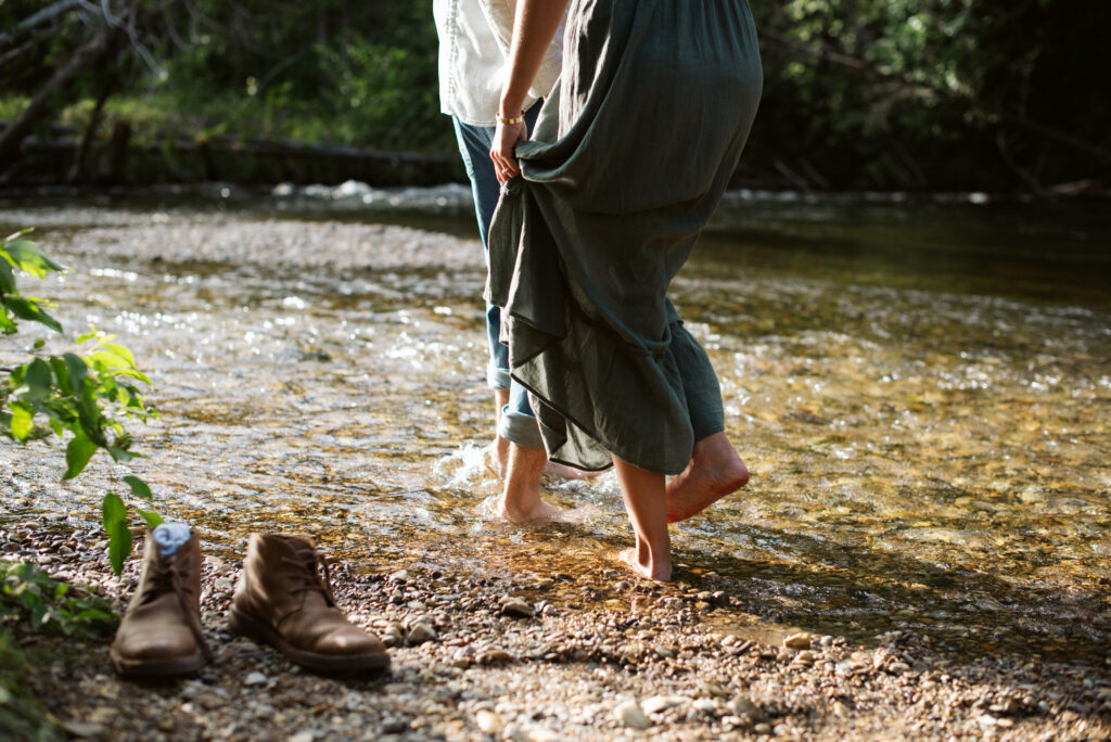 man and woman without shoes walking into a river in traverse city engsgement photos