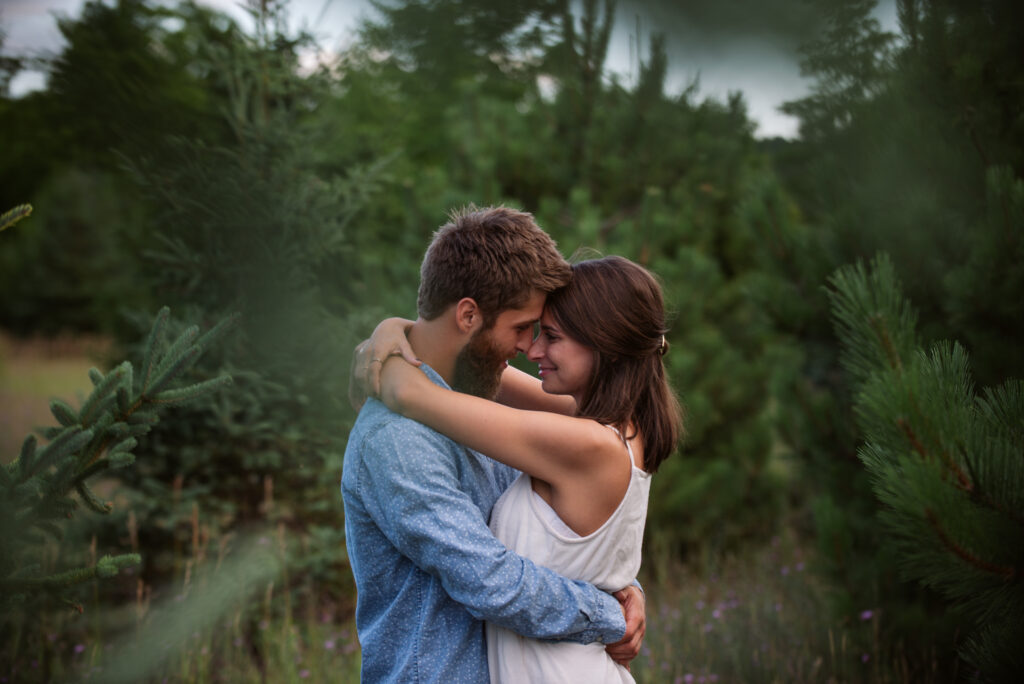 man and woman with their arms around each other in field during traverse city engagement session