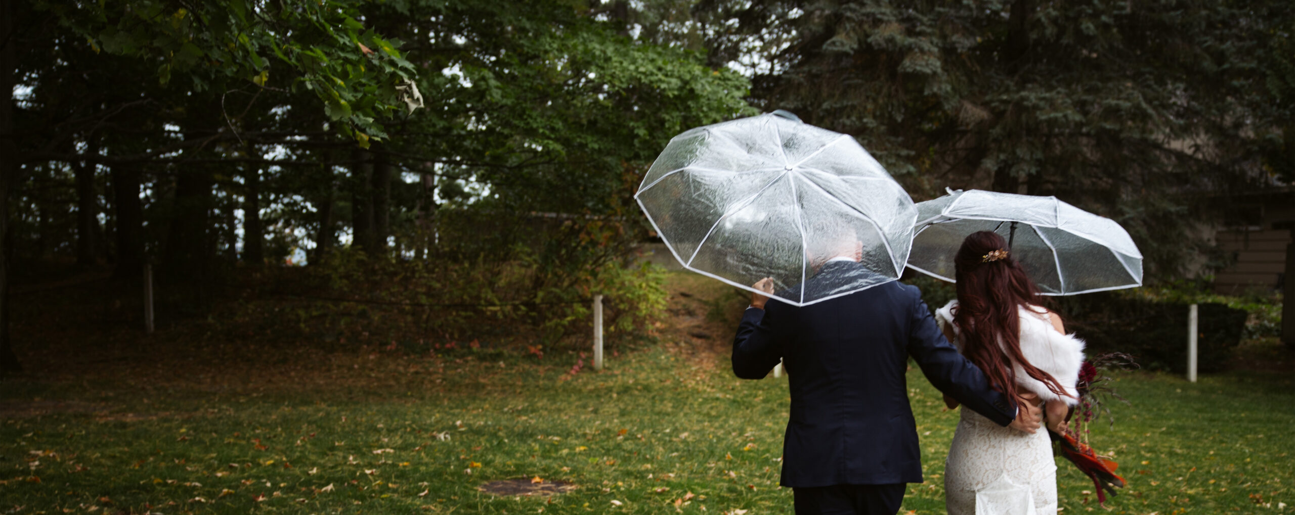 bride and groom walking in the rain with umbrellas at peninsula cellarsin traverse city