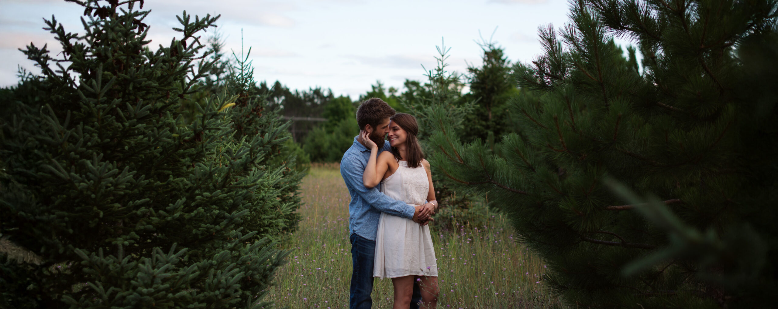 bride and groom holding each other in field in traverse city engagement photos