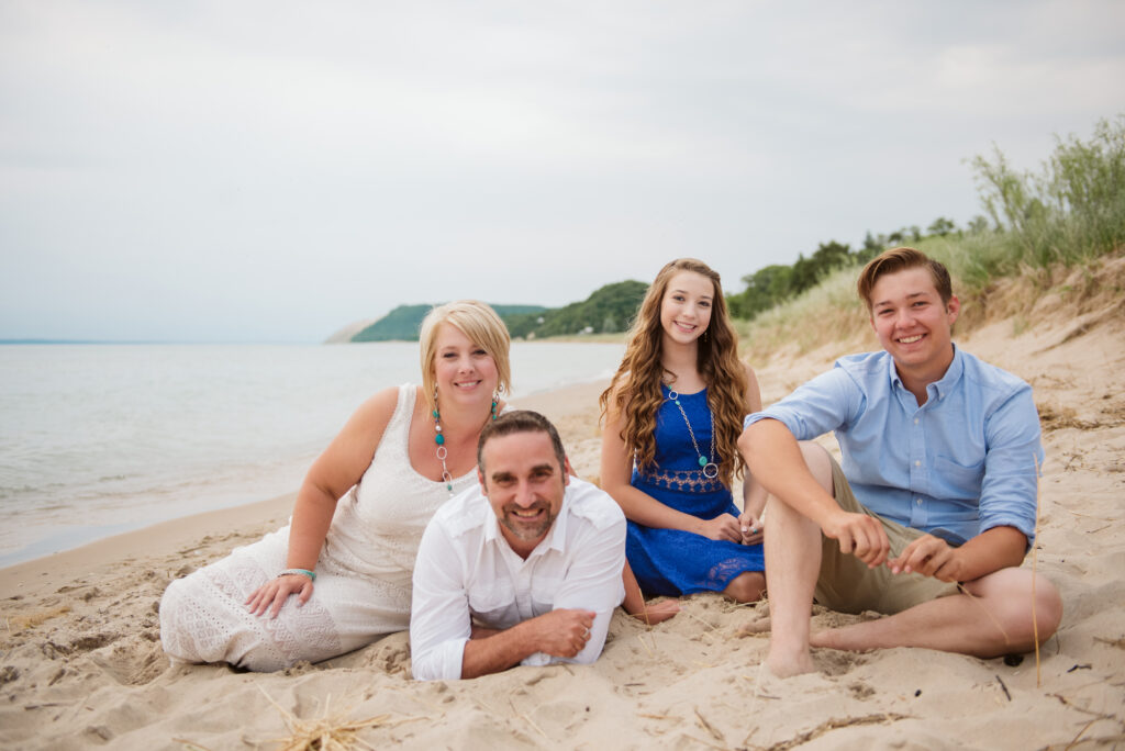 family on lake michigan beach taking family photos with traverse city photographer