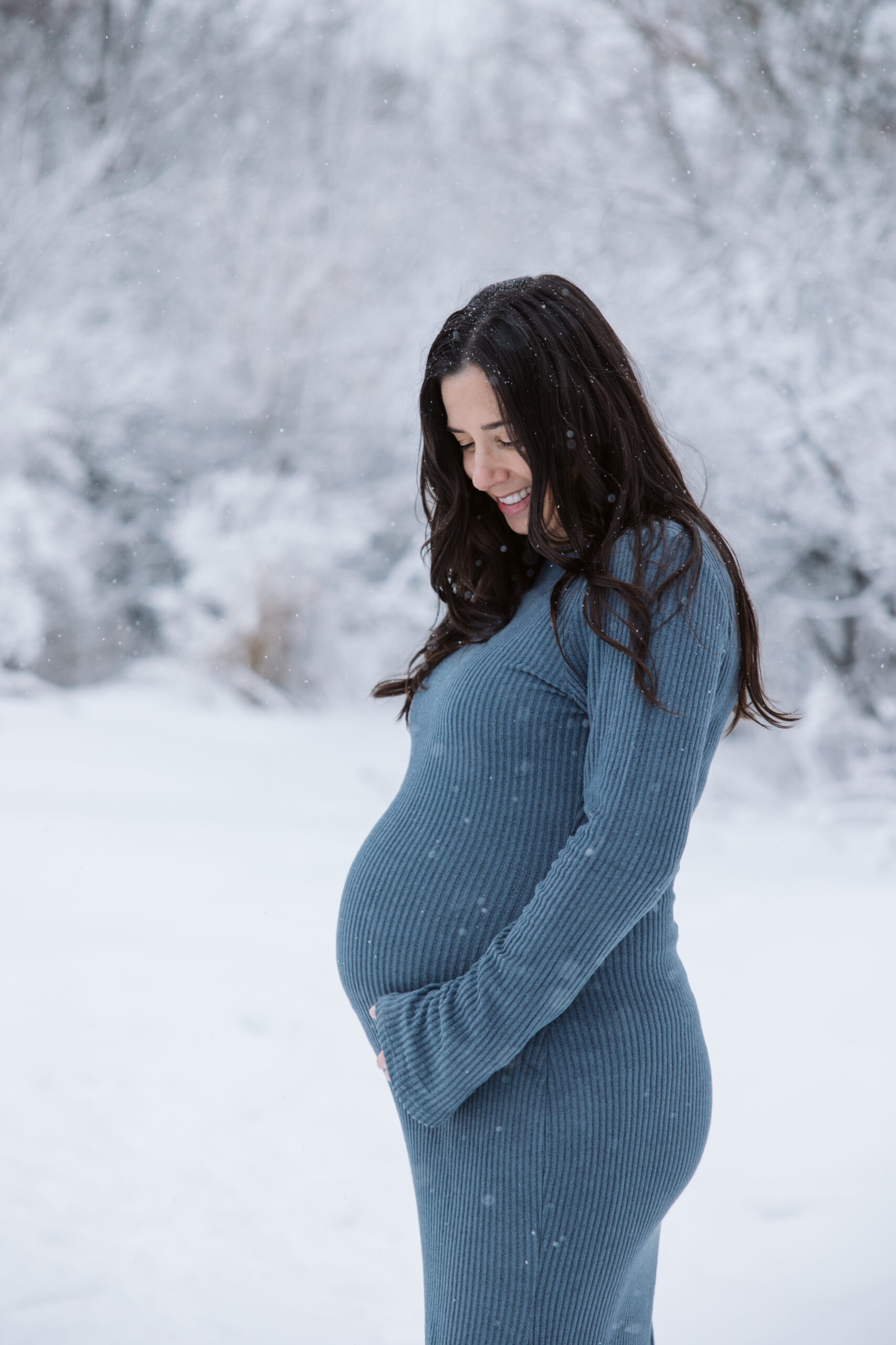 man and woman in the snow during winter maternity photos in traverse city michigan