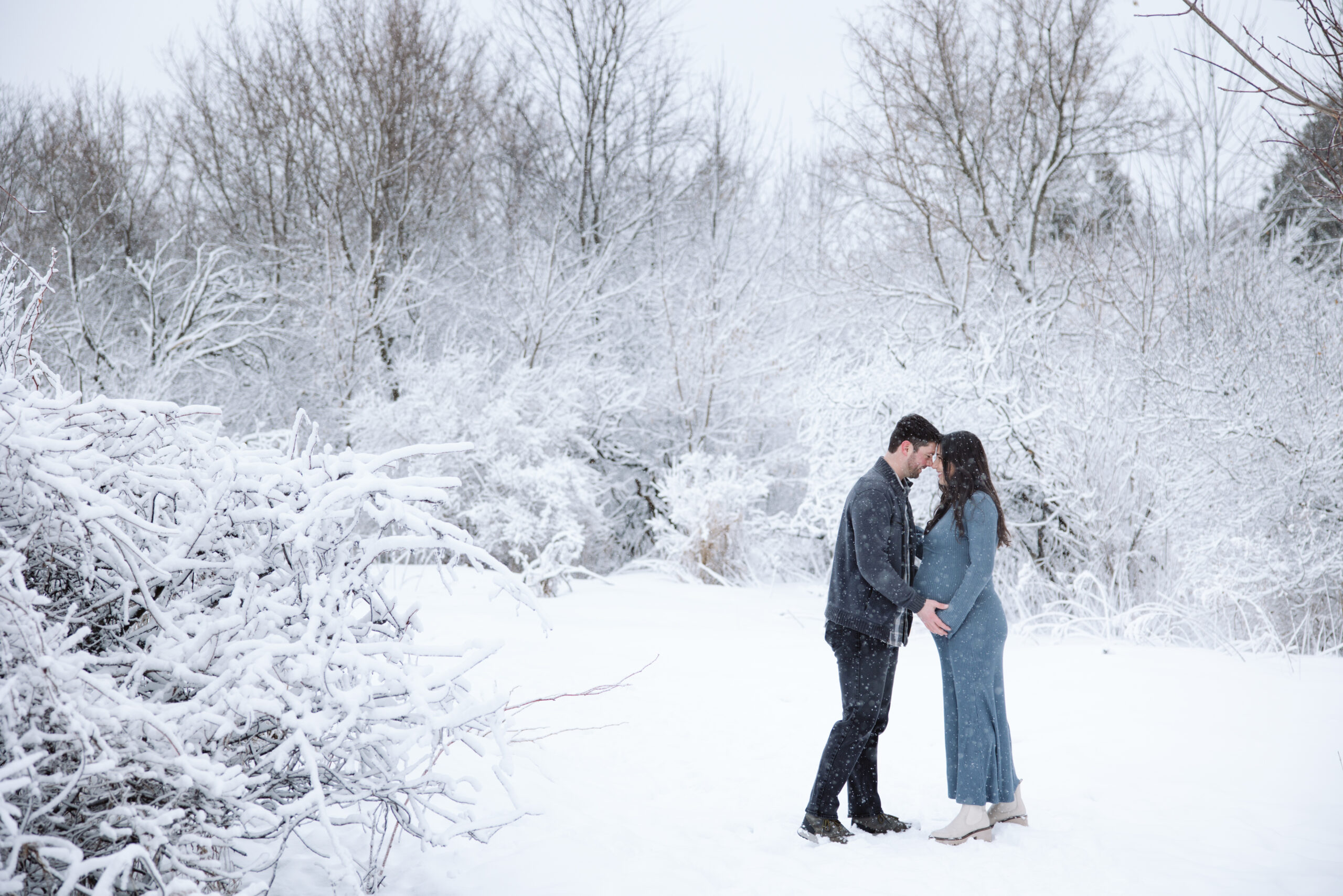 man and woman in the snow during winter maternity photos in traverse city michigan