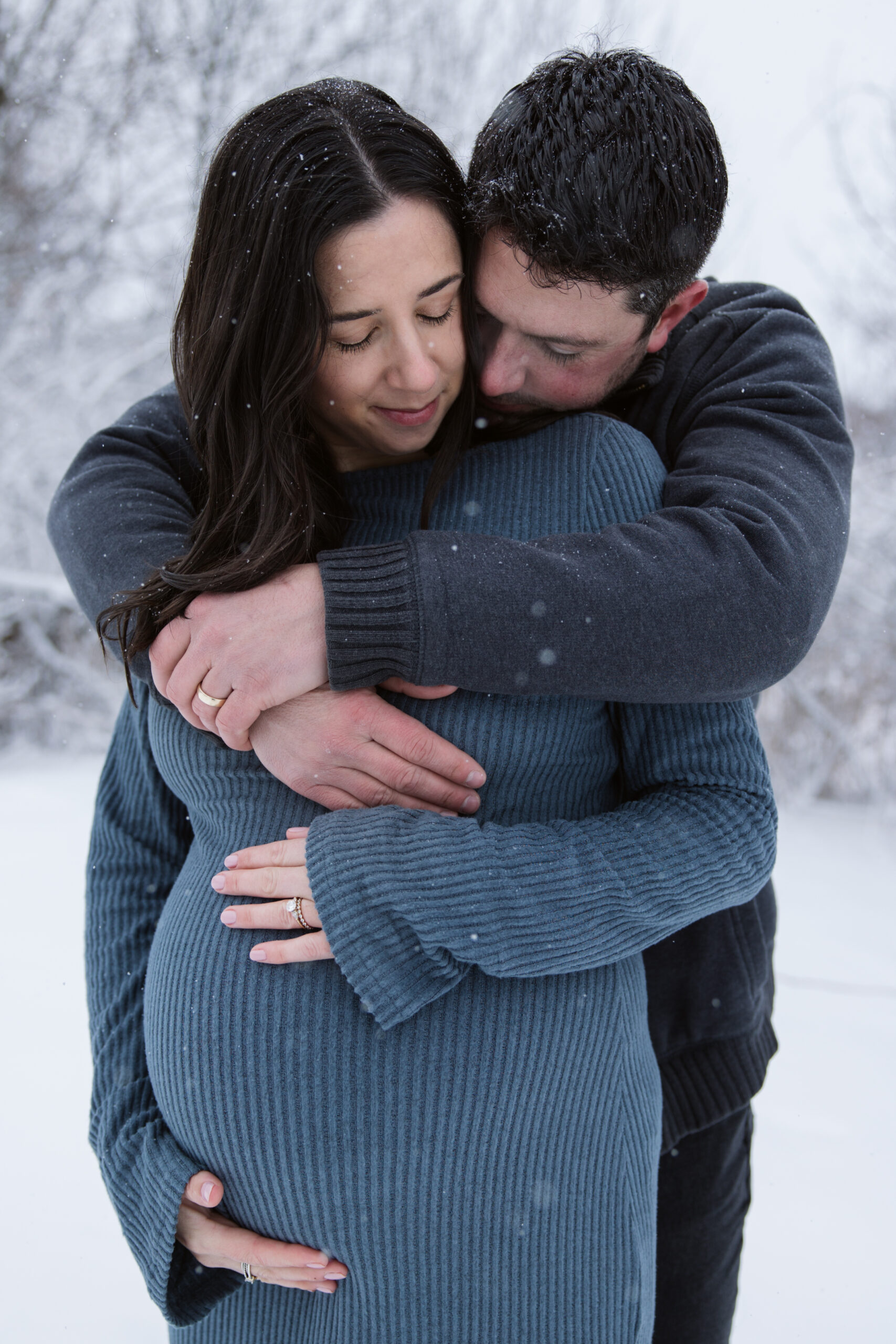 man and woman in the snow during winter maternity photos in traverse city michigan