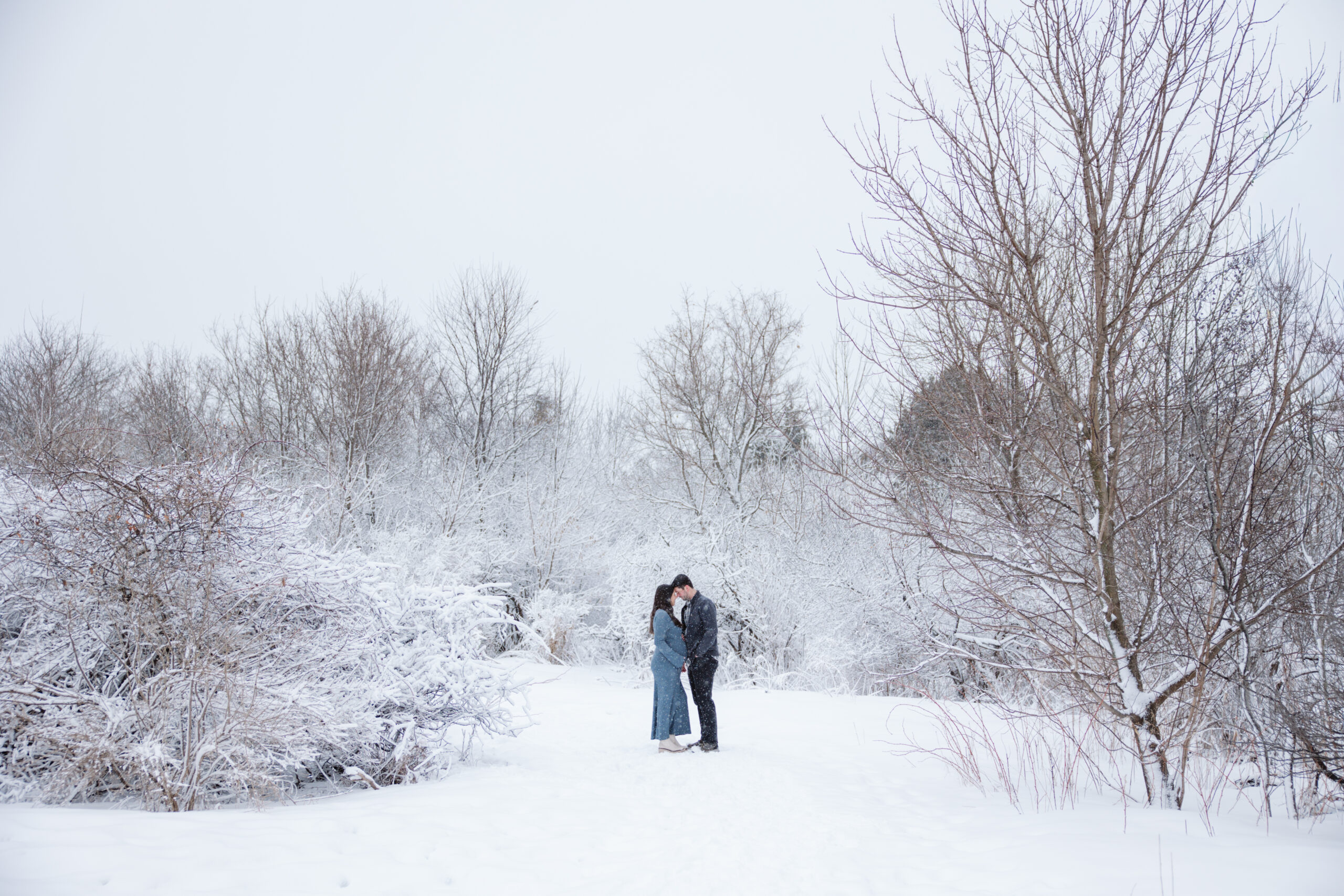 man and woman in the snow during winter maternity photos in traverse city michigan