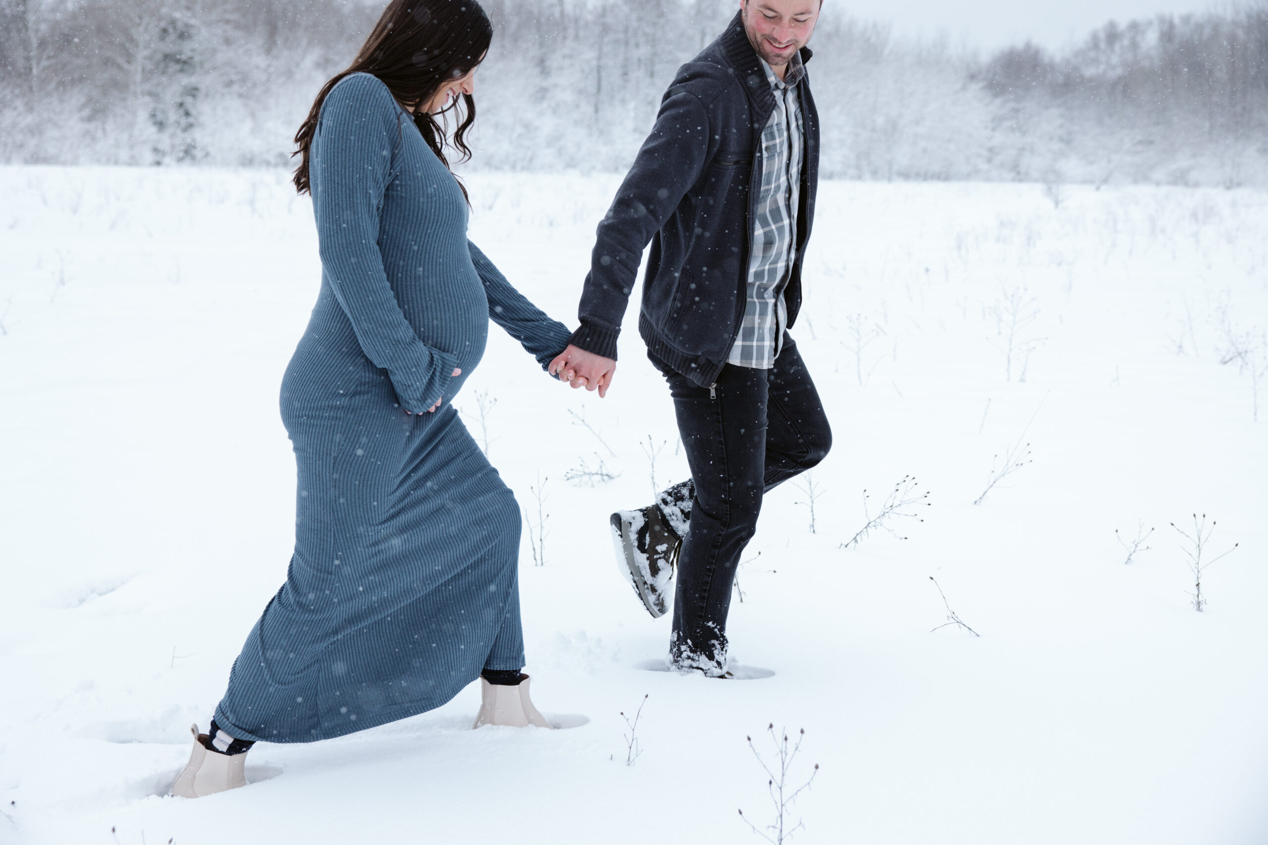 man and woman in the snow during winter maternity photos in traverse city michigan