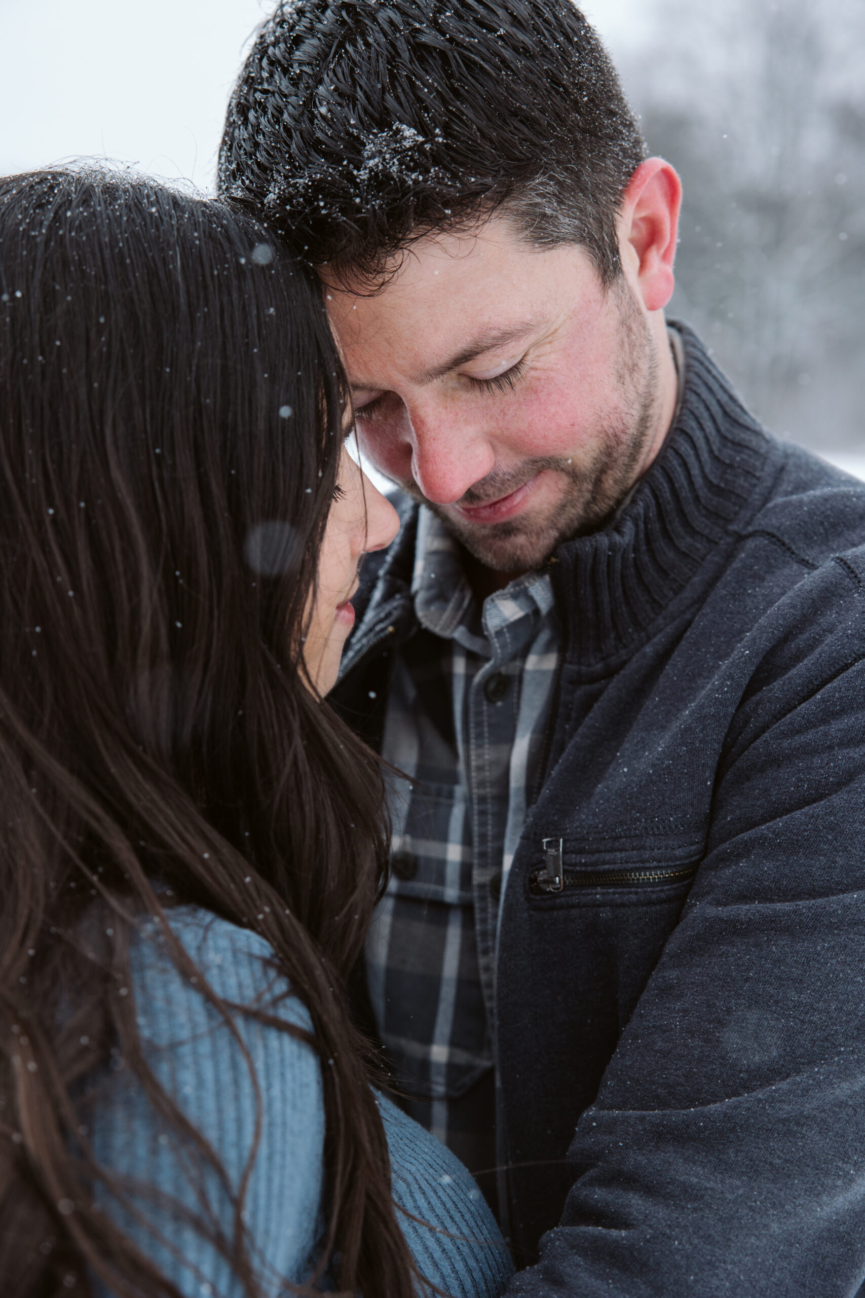 man and woman in the snow during winter maternity photos in traverse city michigan