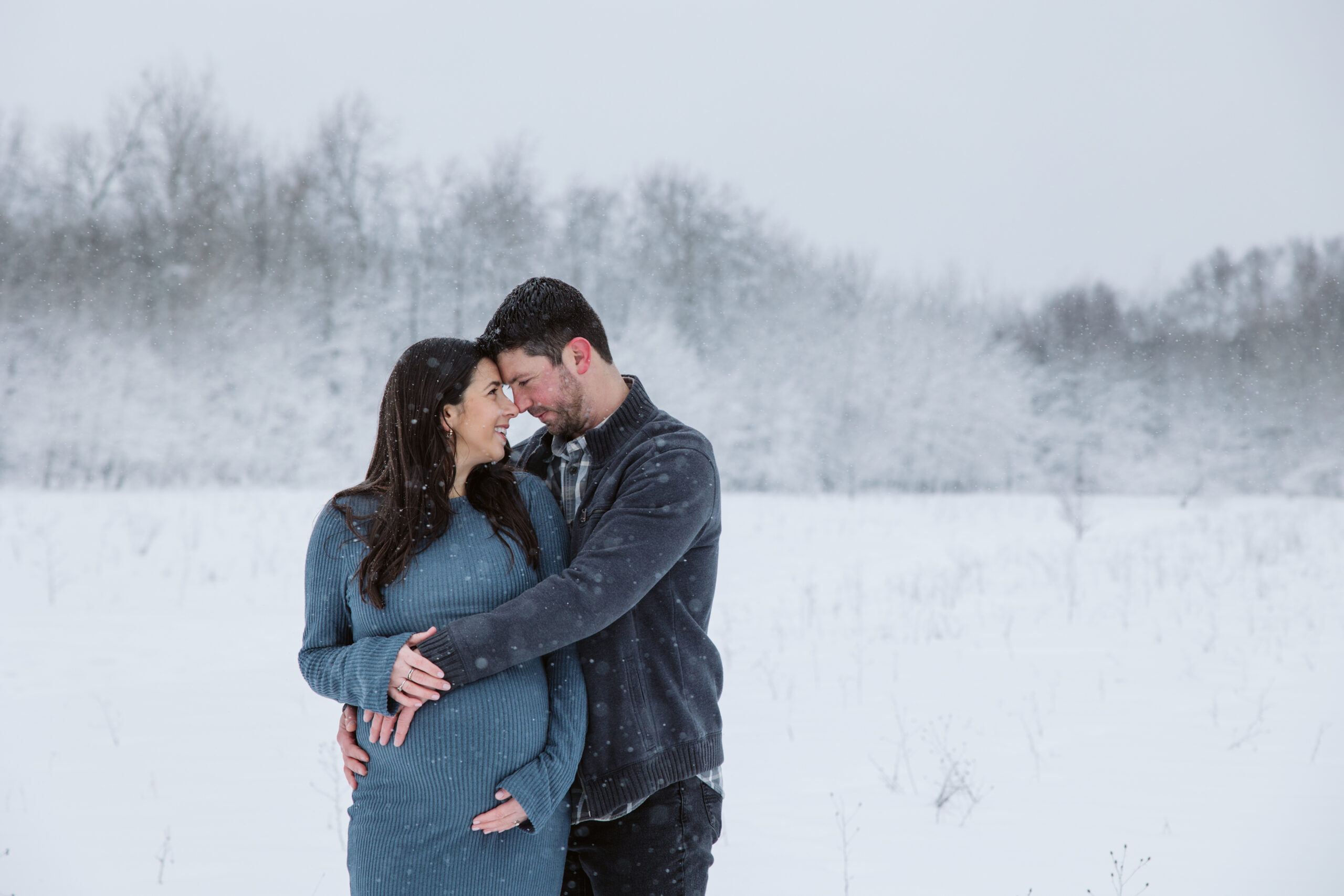 man and woman in the snow during winter maternity photos in traverse city michigan