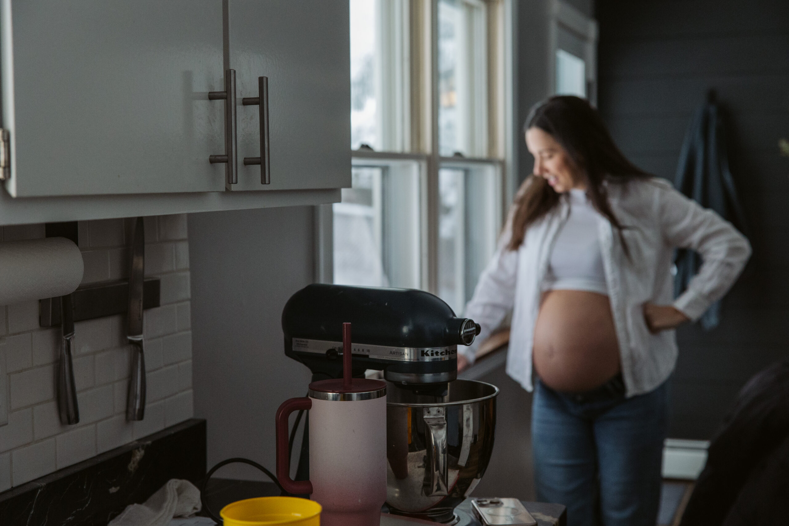 pregnant woman standing at window durning home maternity photos in traverse city michigan